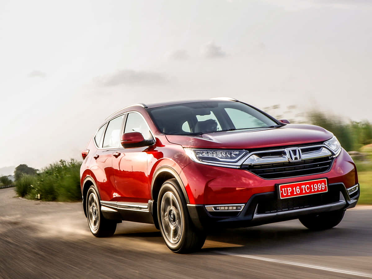 Honda Cr-v 桌布 壁紙 — 一輛鮮紅色的本田CR-V SUV在模糊的綠化和陰天中沿著鄉村道路疾馳。