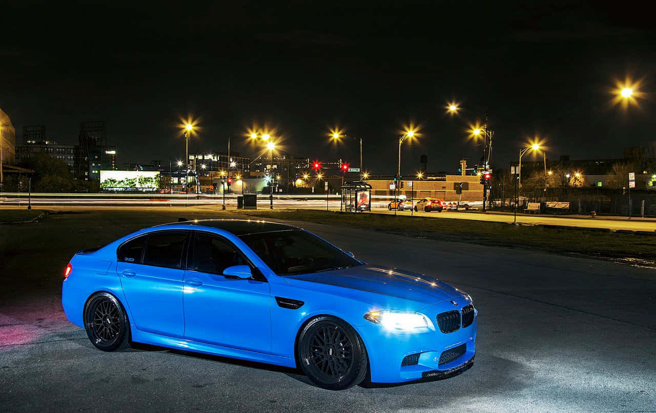 Bmw M5 桌布 壁紙 — 一輛充滿活力的藍色BMW M5跑車在夜晚的城市燈光下閃耀，背景有動態模糊條紋。