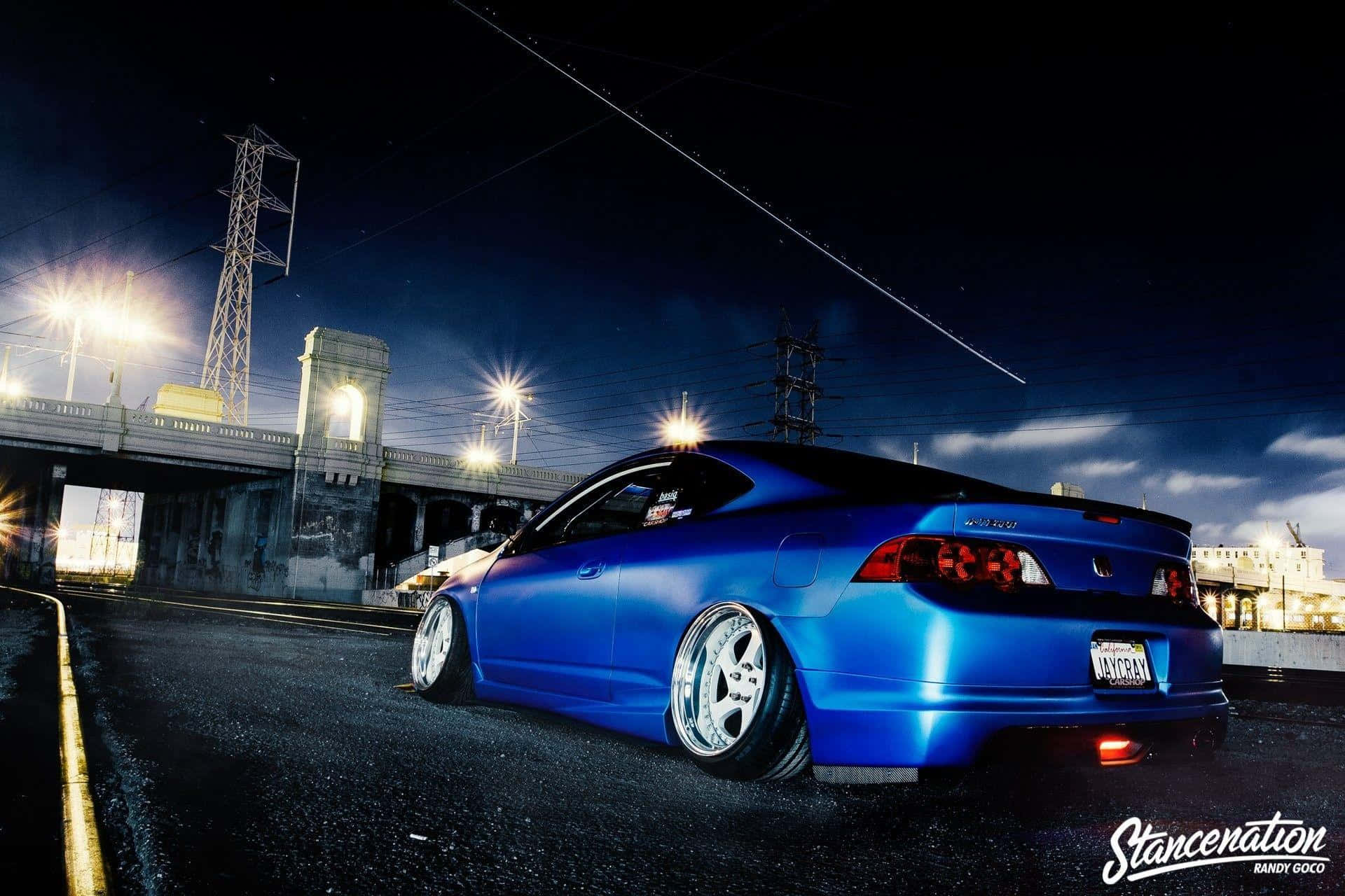 Rsx Type-s 桌布 壁紙 — 一輛充滿活力的藍色改裝跑車在橋下、電線和雲層下的夜燈中閃耀。
