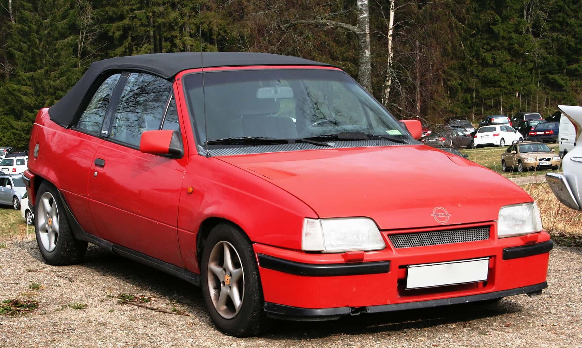 Opel Kadett 桌布 壁紙 — 一輛鮮紅色的Opel Cabriolet停泊在碎石上，背景有樹木。