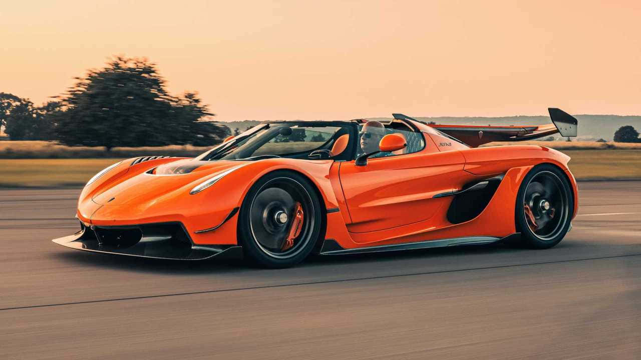  壁紙 — 一輛鮮豔的橙色Koenigsegg Jesko Absolut在日落時分沿著道路疾馳，帶有模糊的動態和溫暖的金色光線。