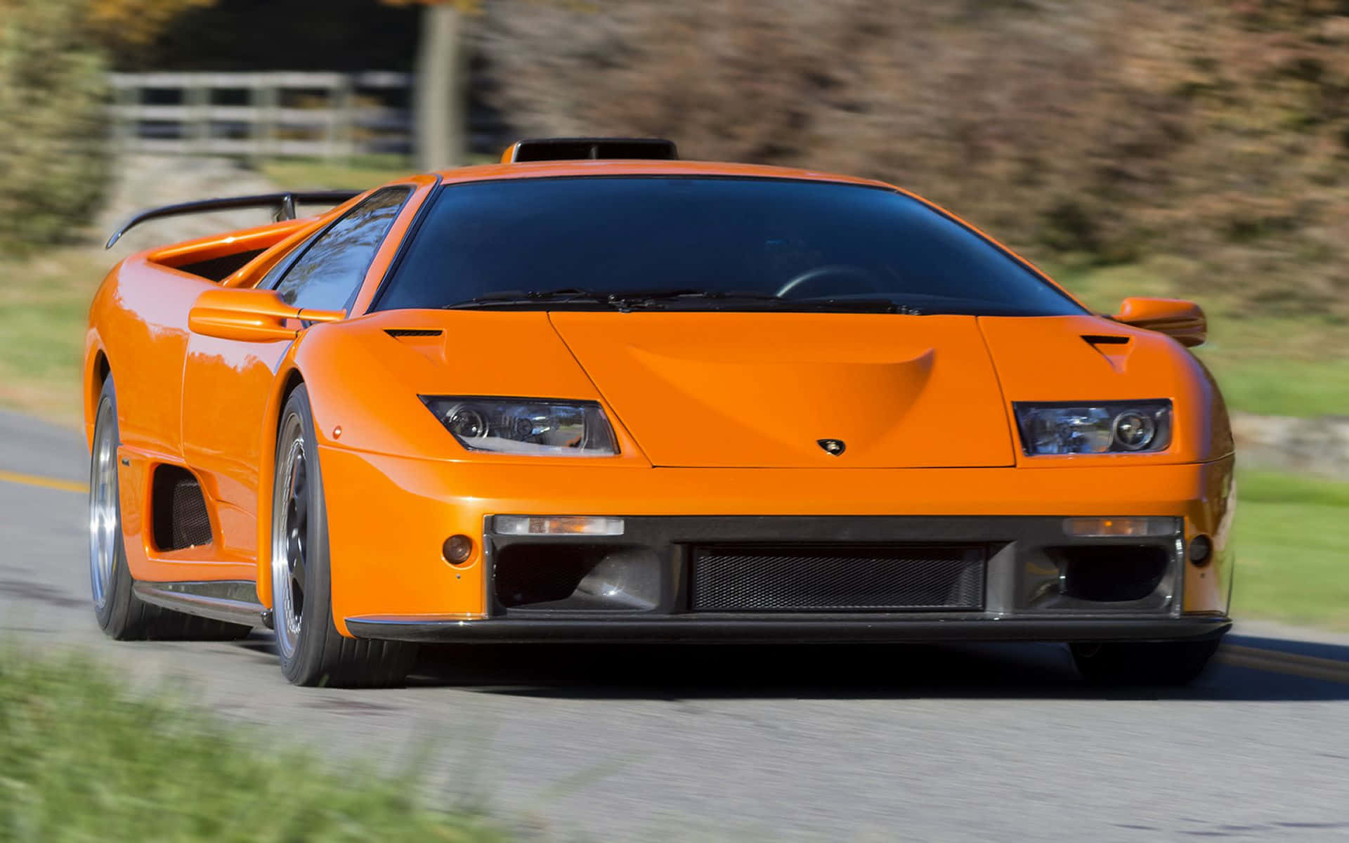 Lamborghini Diablo 桌布 壁紙 — 一輛鮮橙色的林寶堅尼 Diablo 在蜿蜒的道路上疾馳，背景是模糊的綠意。