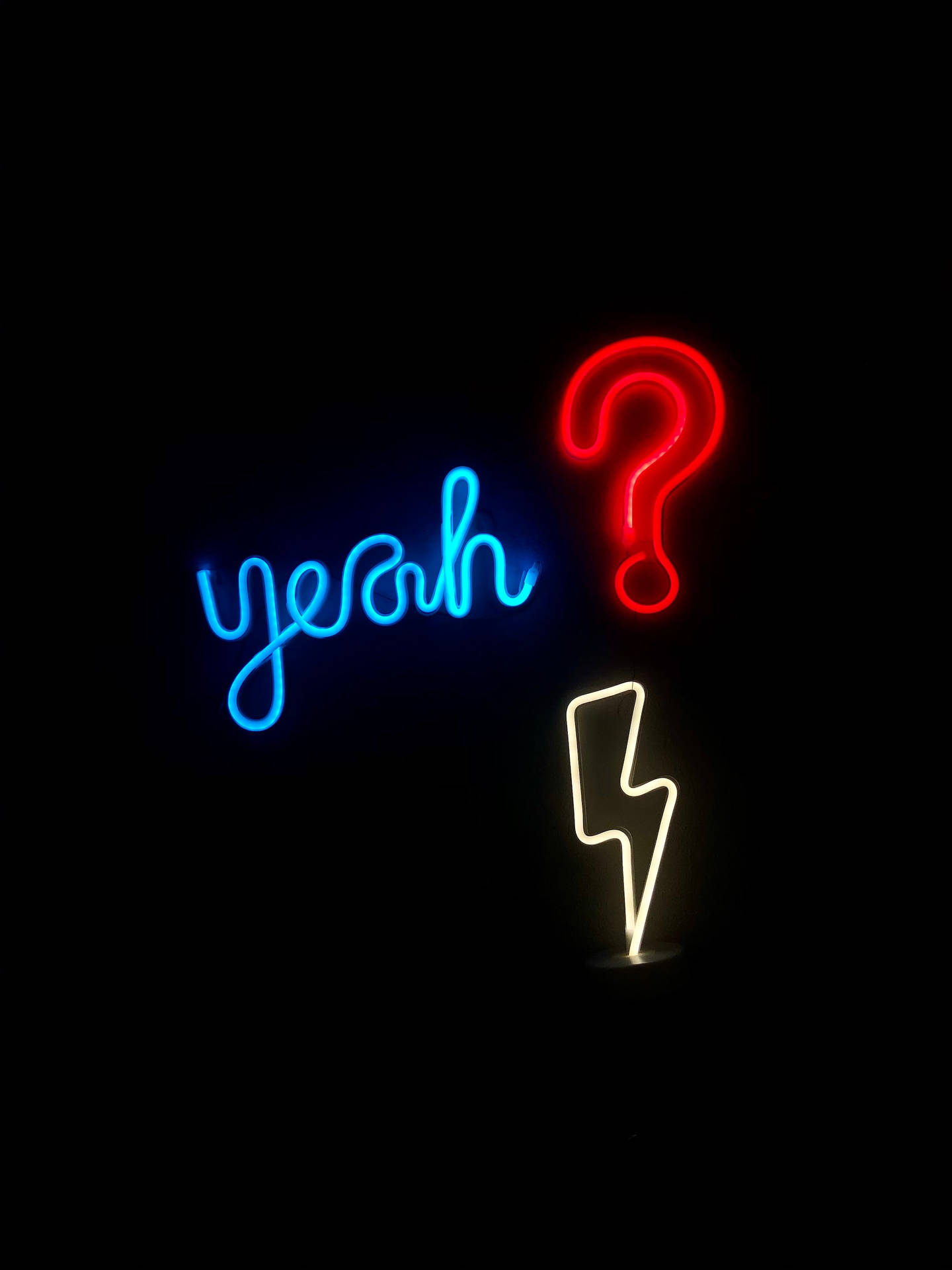 霓虹燈牌在黑暗環境中顯示 yeah、問號和閃電。