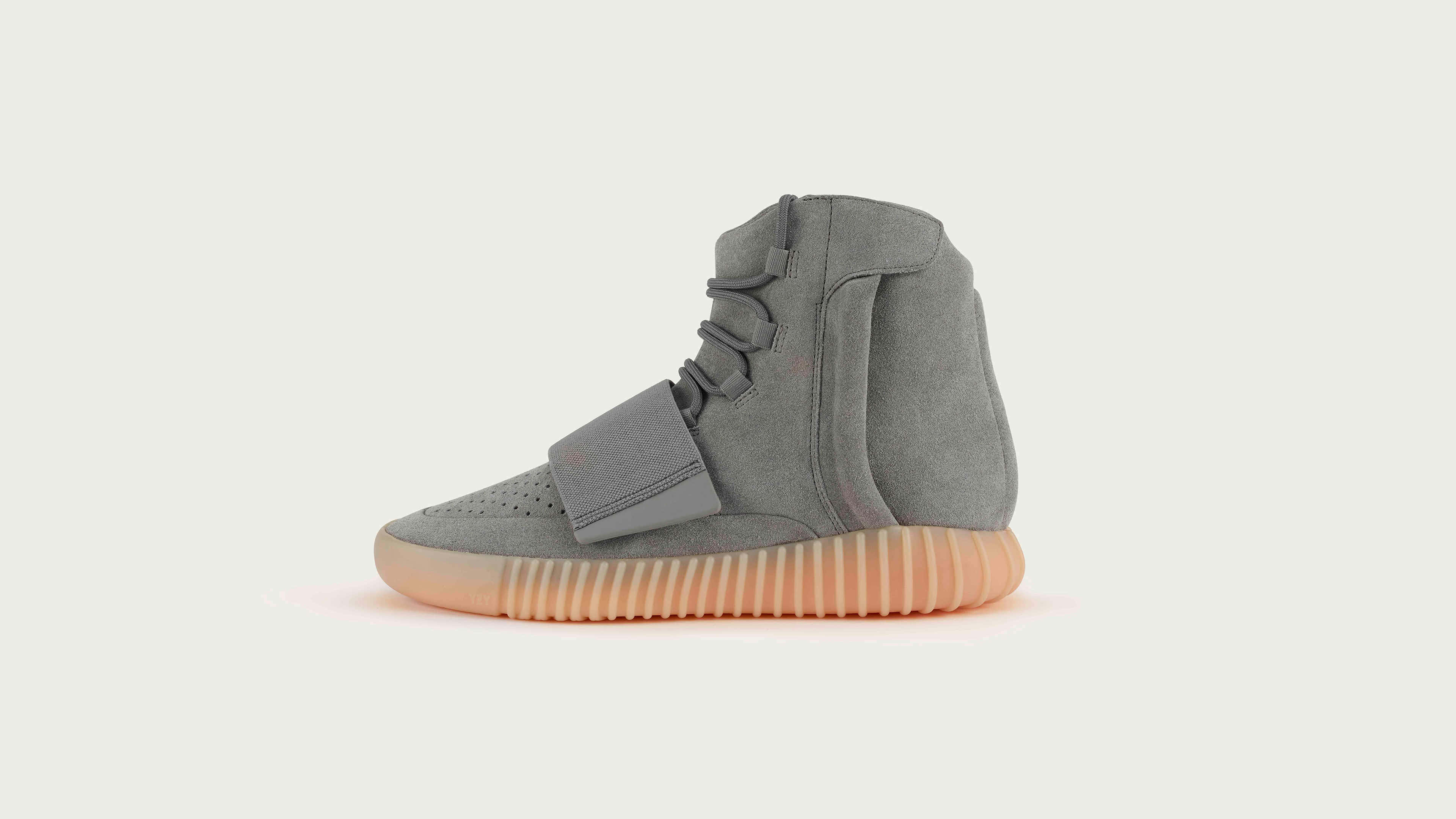 以經典Yeezy提升時尚品味 壁紙 — 一雙時尚的灰色高筒運動鞋，搭配蜜桃色鞋底，孤立地立在柔和的米白色背景上。