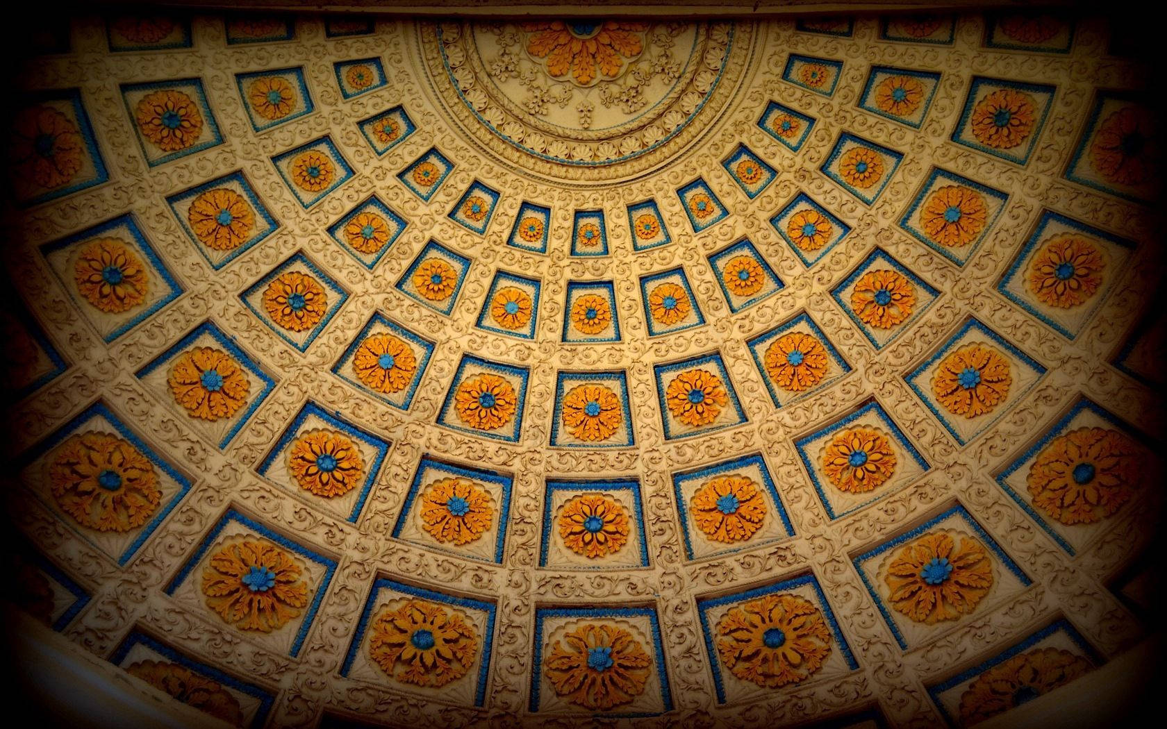 Yellow Ceiling Design 壁紙 — 一個裝飾華麗的圓頂天花板，金色和藍色的重複花卉徽章鑲嵌在奶油色灰泥上。