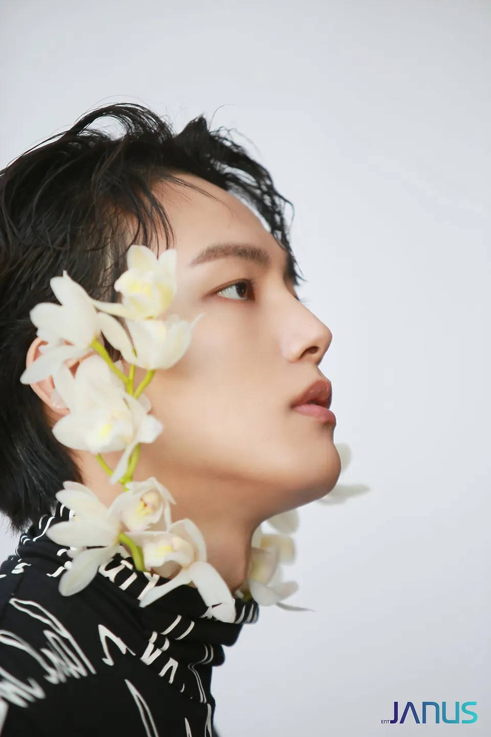 Yeo Jin Goo 側臉特寫 壁紙 — 一位黑髮年輕男子抬頭仰望，白色蘭花如瀑布般垂落在他肩上，背景是純白色。
