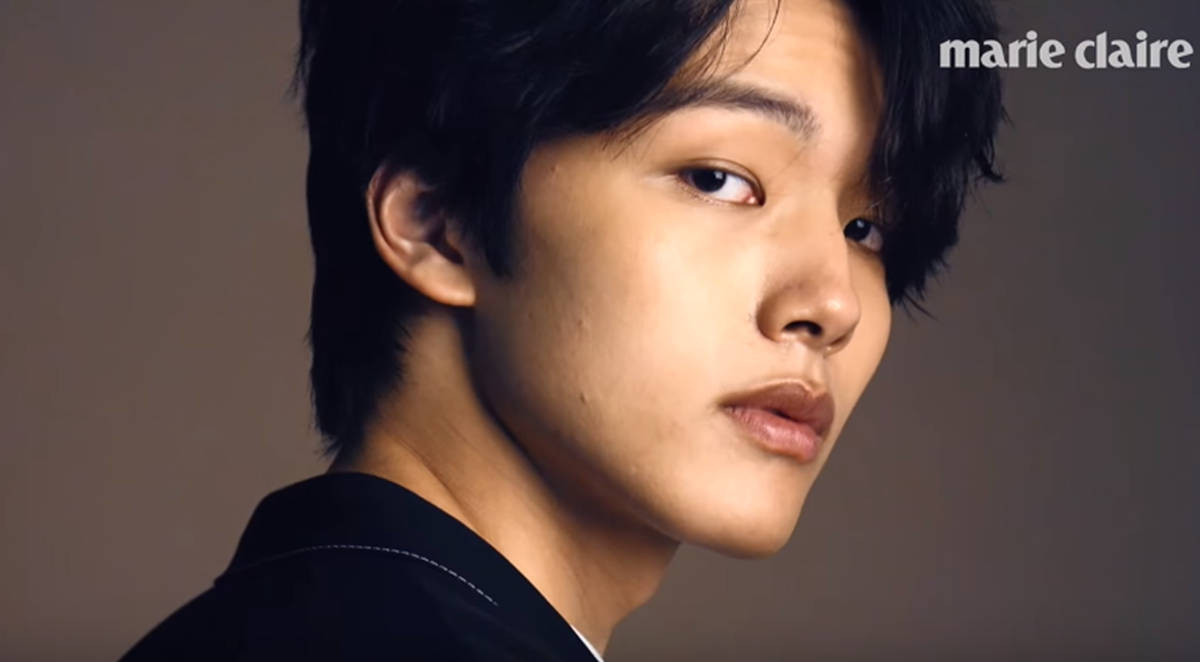 Yeo Jin Goo 為 Marie Claire 拍攝時的優雅姿態 壁紙 — 一位深色頭髮的年輕男子在柔和的灰色背景上若有所思地越過肩膀凝視。