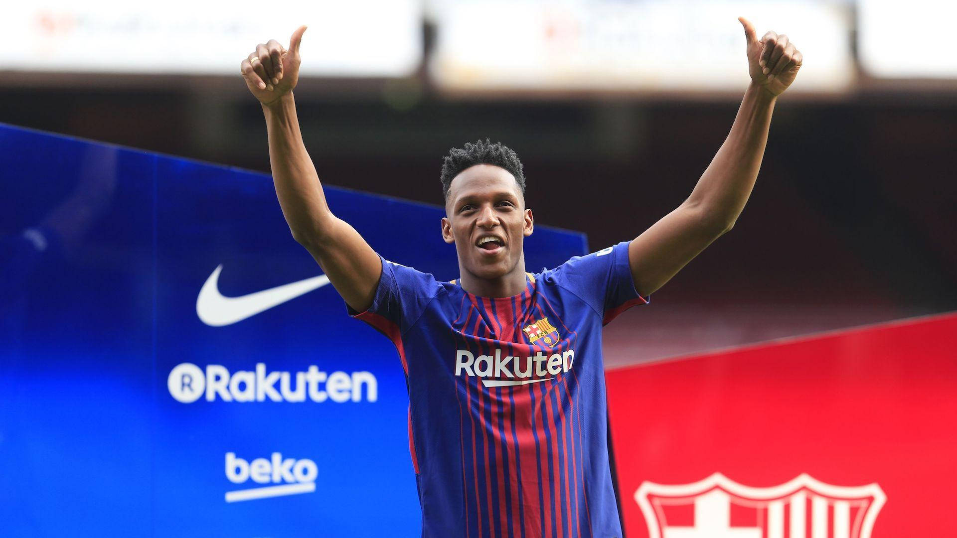 Yerry Mina 雙手比讚 壁紙 — 一位身穿藍紅間條球衣的快樂足球員在球場上高舉雙臂，豎起兩個大拇指。