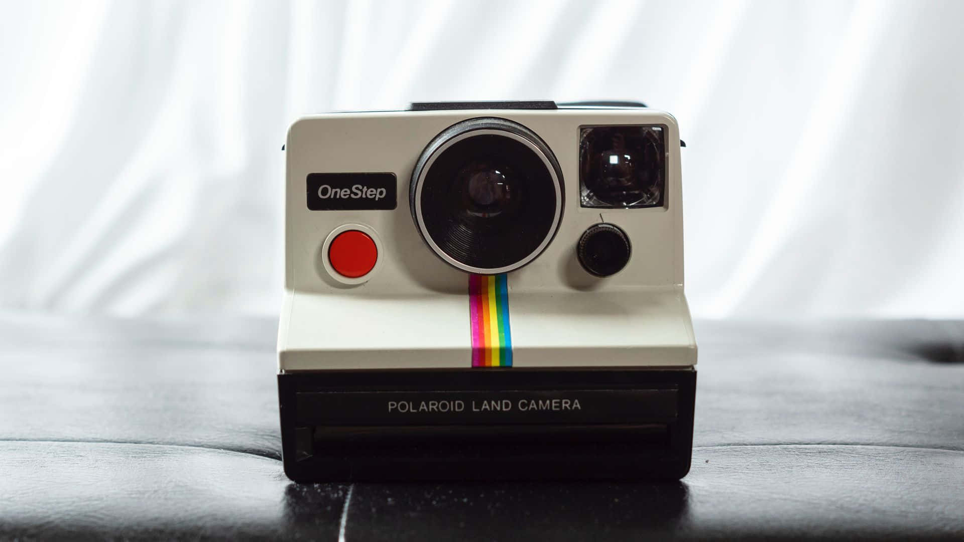 一部復古Polaroid OneStep相機在皮革表面上，背景是白色窗簾。 — 寶麗來 GIF 壁紙
