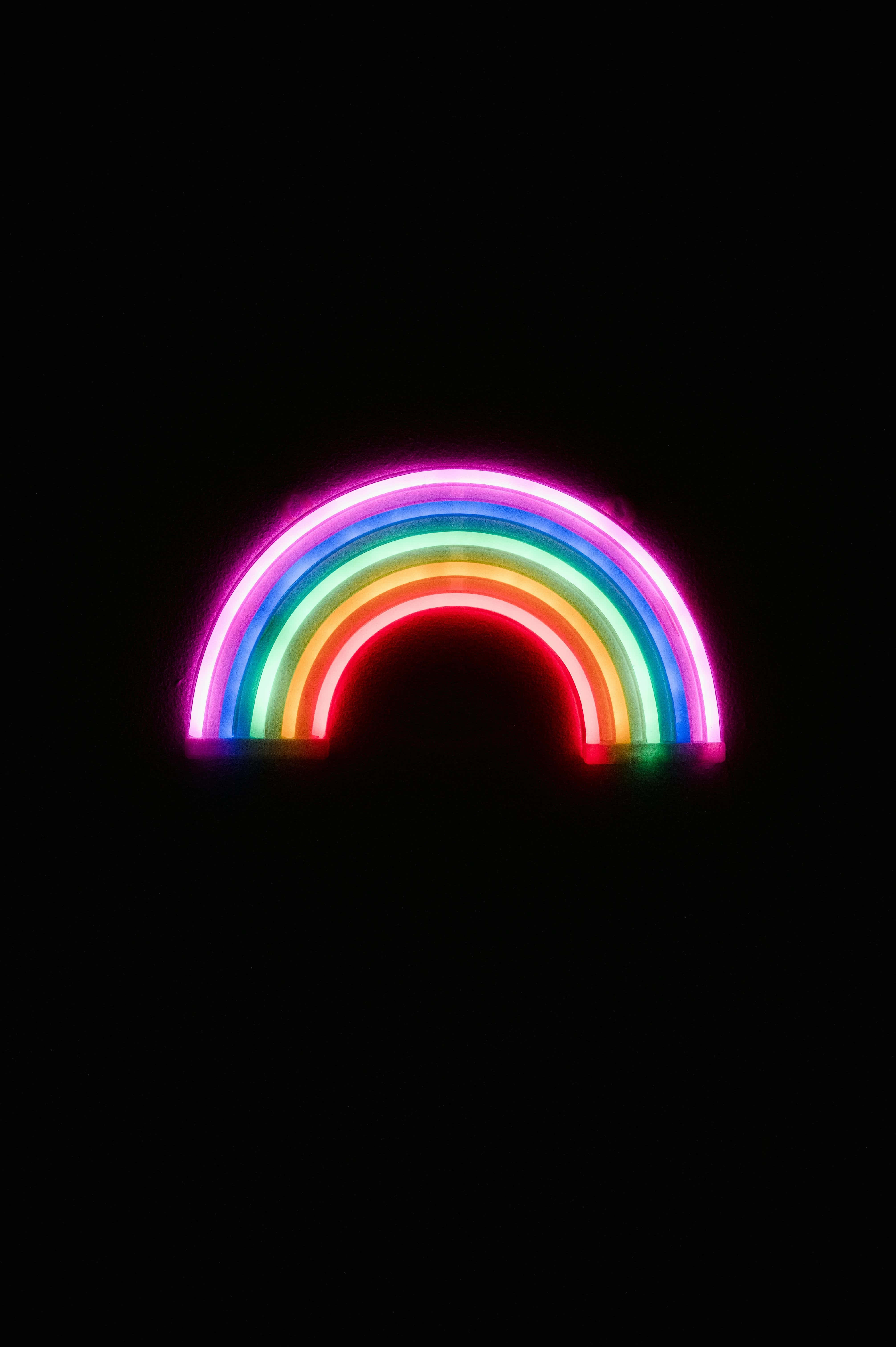 Neon Rainbow 桌布 壁紙 — 一道充滿活力的霓虹彩虹在漆黑背景上拱起，散發著電光般的色彩。
