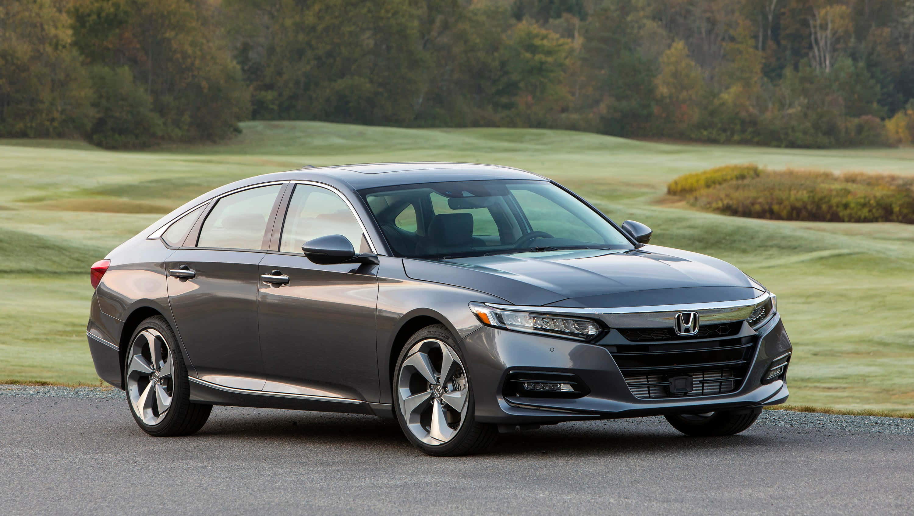 Honda Accord 桌布 壁紙 — 一架時尚的灰色本田雅閣轎車停泊在碎石路上，旁邊是修剪整齊的綠色高爾夫球場，背景有秋天的樹木。