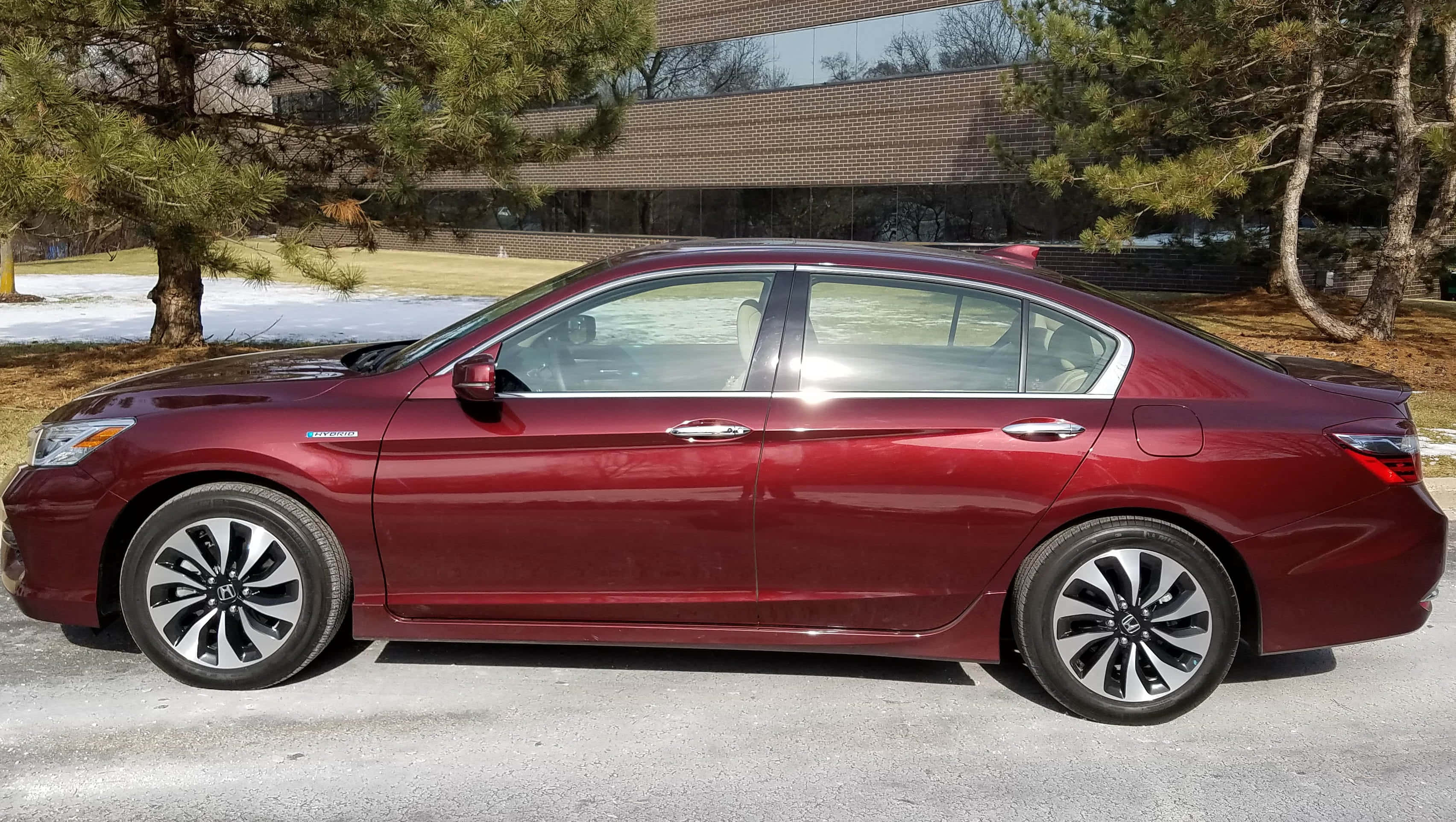 Honda Accord 桌布 壁紙 — 一架時尚的栗色轎車停泊在雪地車道上，旁邊有松樹和現代磚砌建築。