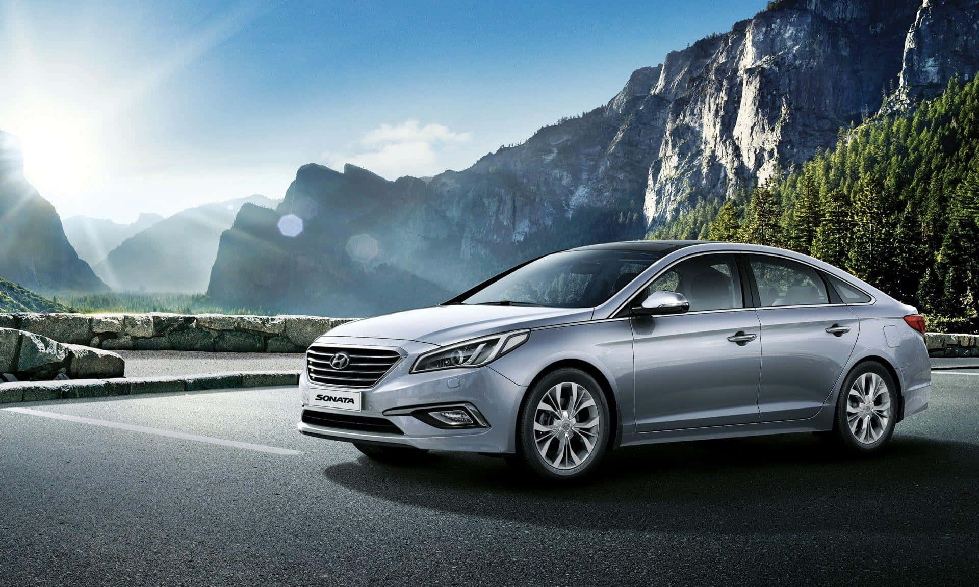 Hyundai Sonata 桌布 壁紙 — 一架時尚的銀色現代Sonata轎車停泊在山路上，背景有太陽光暈和崎嶇的懸崖。