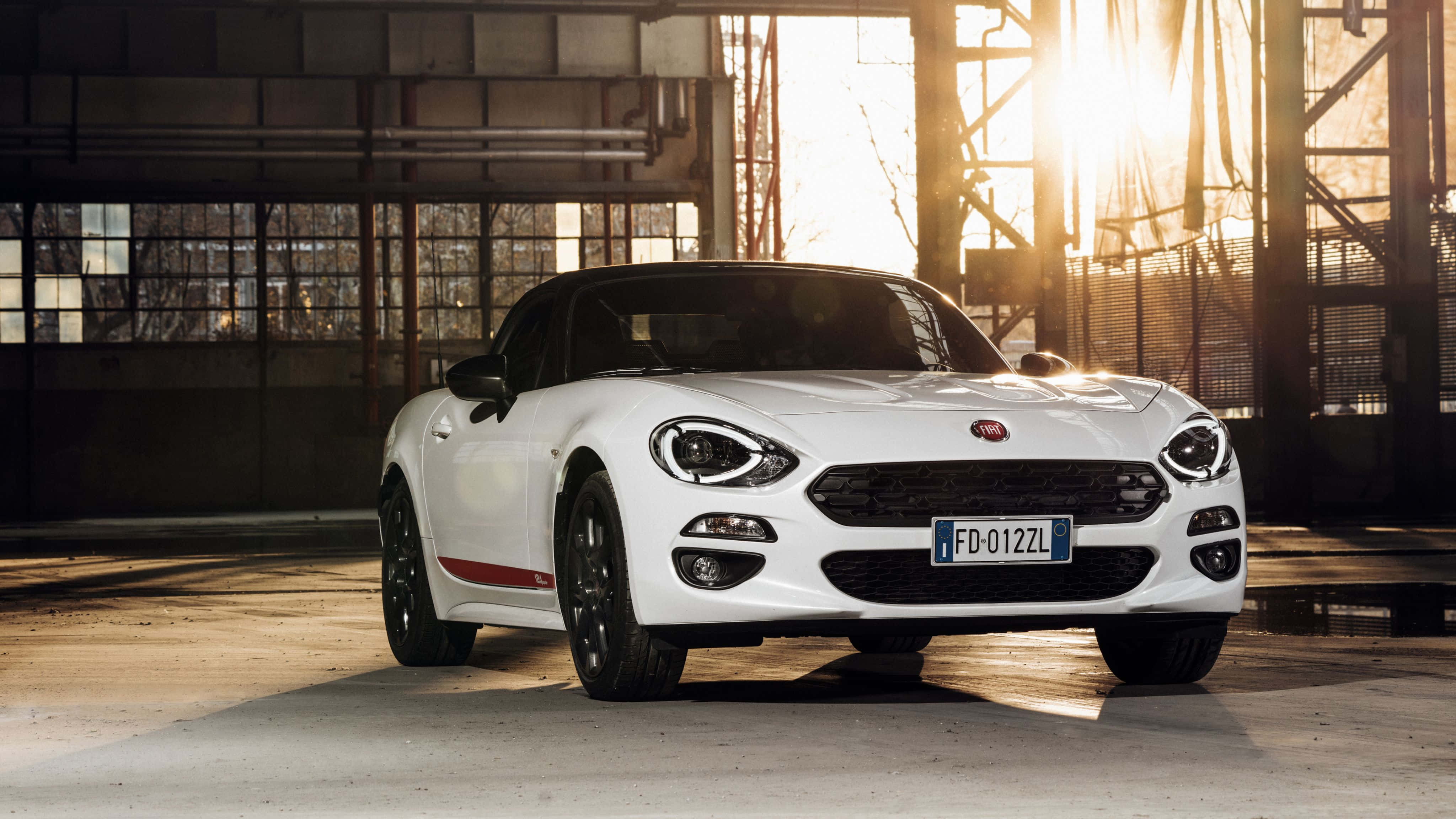 Fiat 500l 桌布 壁紙 — 一架時尚的白色Fiat 124 Spider開篷車停在工業倉庫內，金色陽光透過窗戶灑進來。