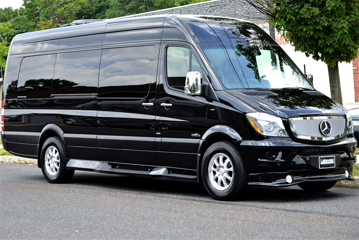Mercedes Benz Sprinter 桌布 壁紙 — 一架時尚的黑色 Mercedes-Benz Sprinter 客貨車停在瀝青路上，背景有樹木和磚砌建築。