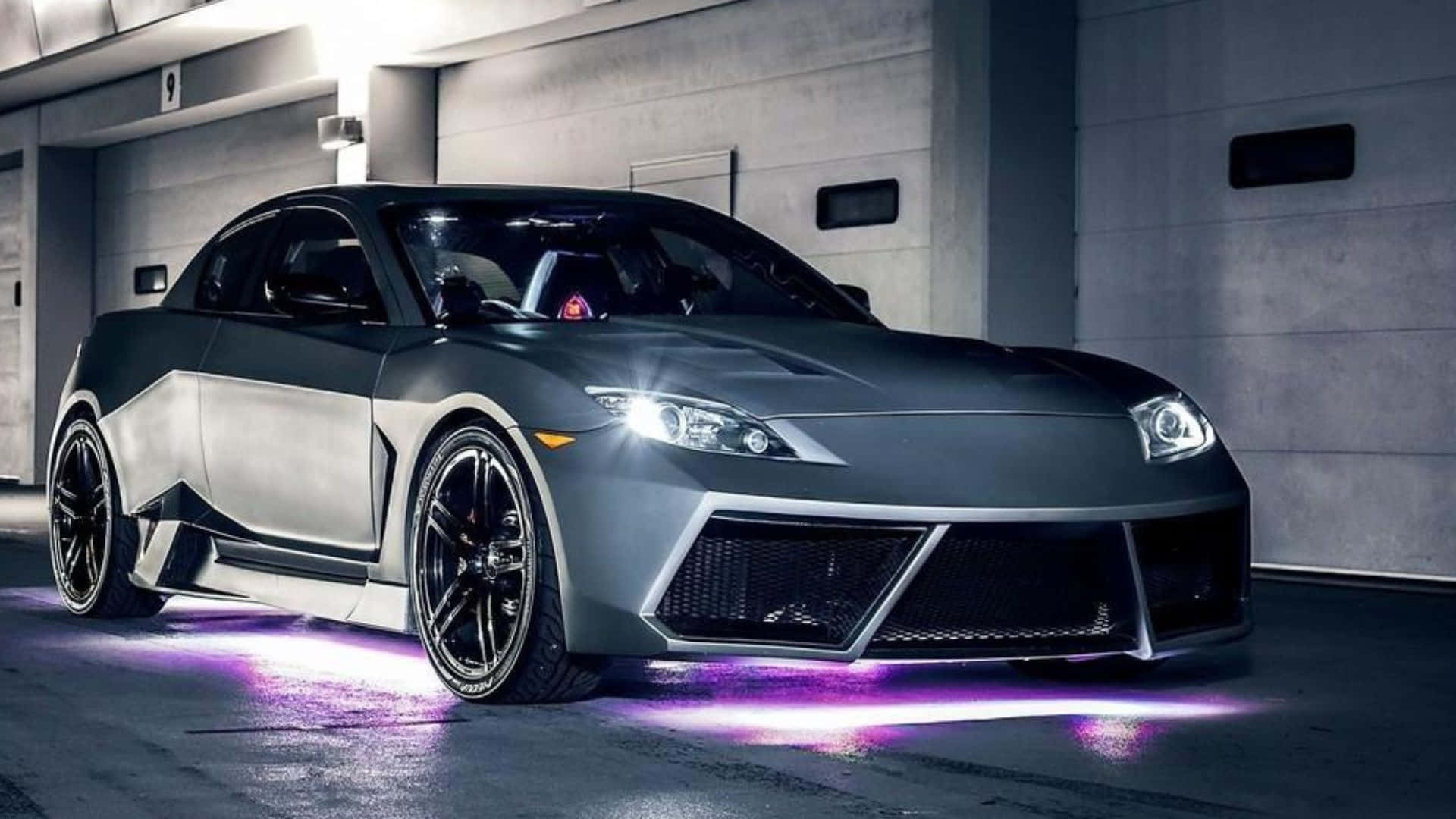 Mazda Rx-8 桌布 壁紙 — 一架光滑的啞光灰色跑車，帶有發光的紫色底盤燈，停放在昏暗的混凝土車庫中。