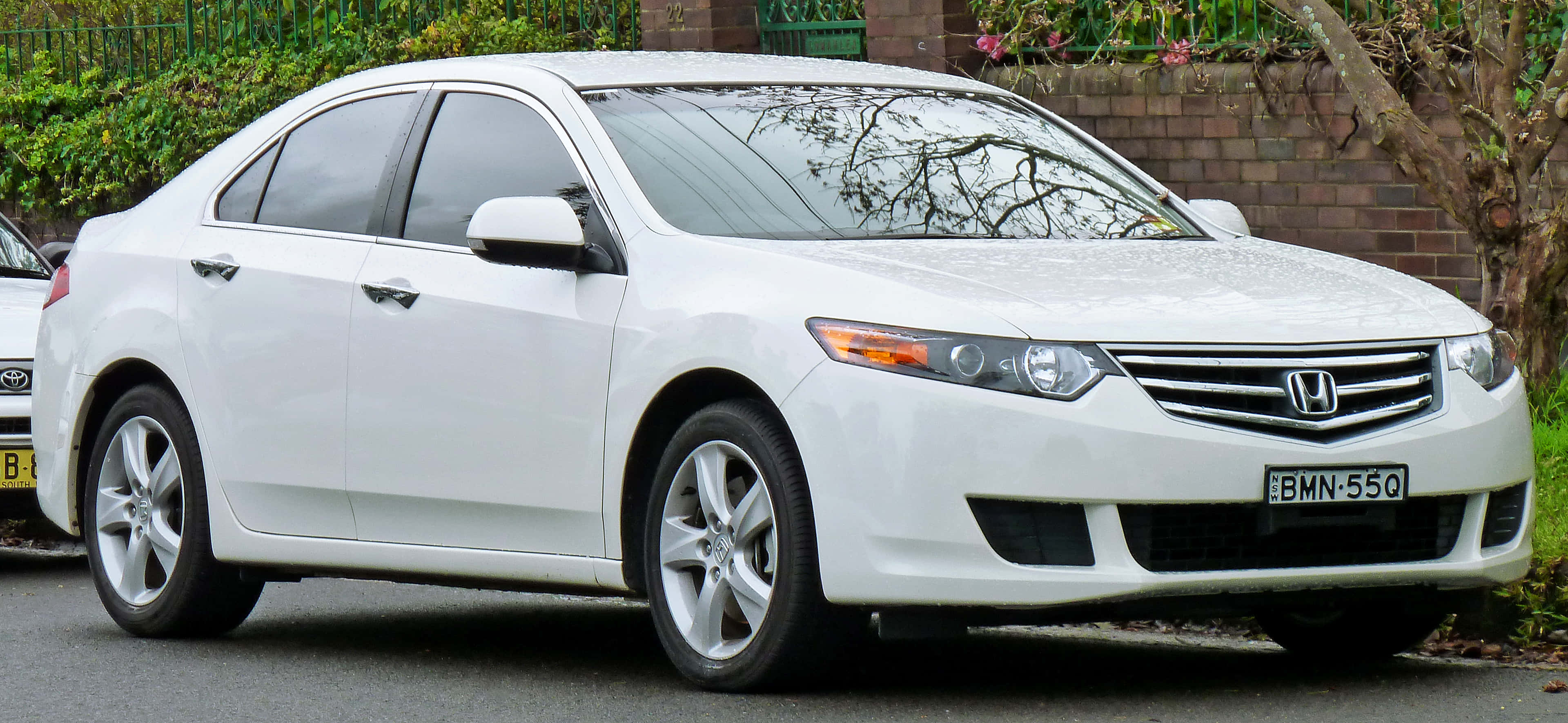 Honda Accord 桌布 壁紙 — 一架純白色本田雅閣房車停泊在磚牆和綠化旁的街道上。