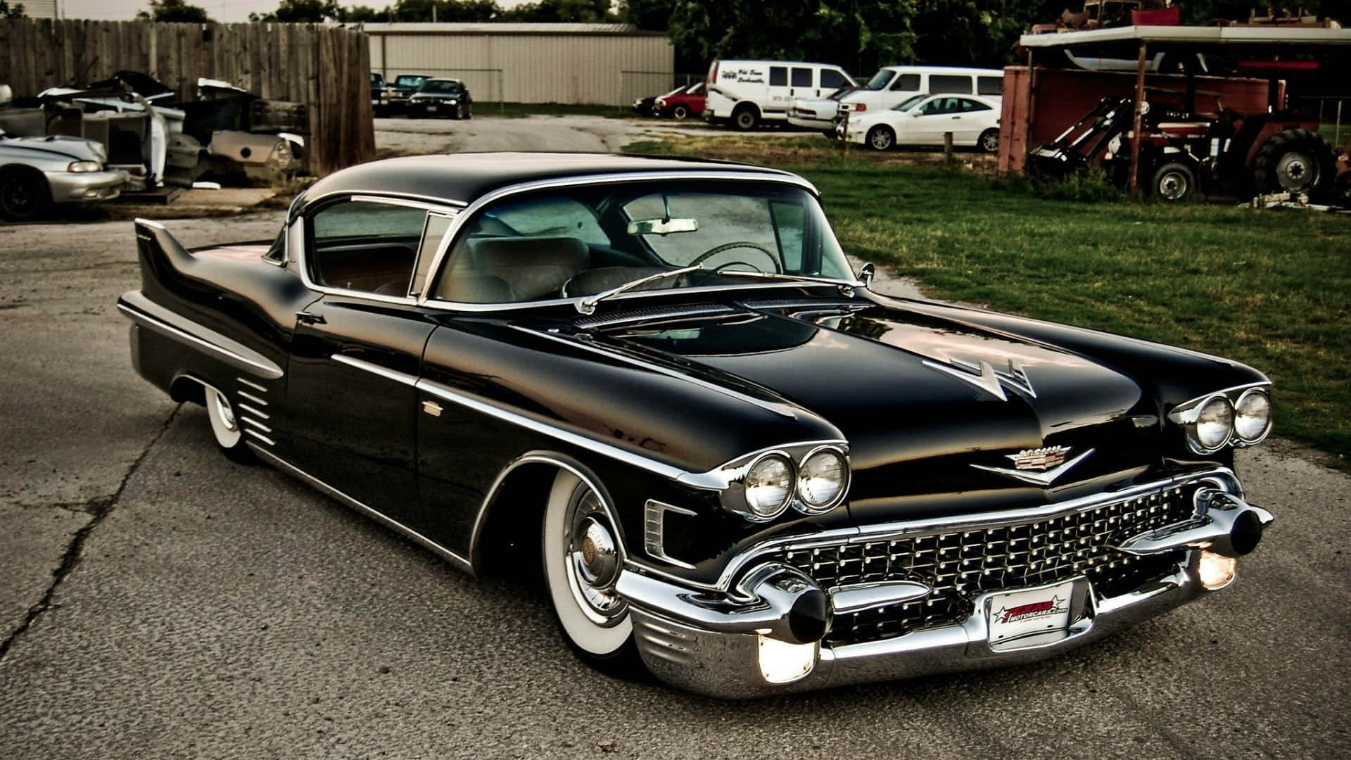 Cadillac Eldorado 桌布 壁紙 — 一架閃亮黑色1959年凱迪拉克，帶有鍍鉻裝飾和白色輪胎，停在鄉村庭院破裂的瀝青上。