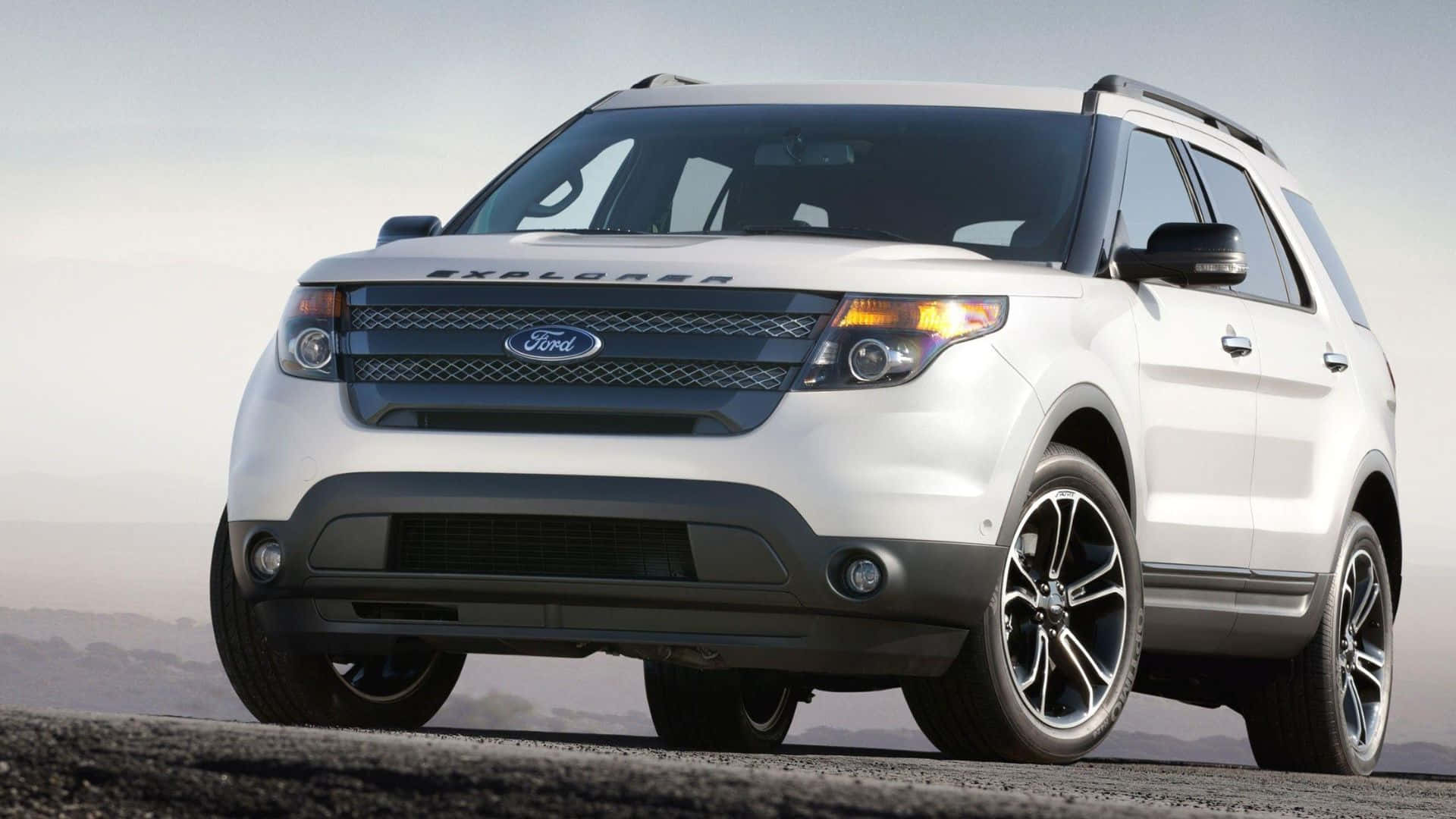 Ford Edge 桌布 壁紙 — 一架時尚的白色福特 Explorer SUV 停泊在鋪砌道路上，背景是朦朧的山脈，天空明亮。
