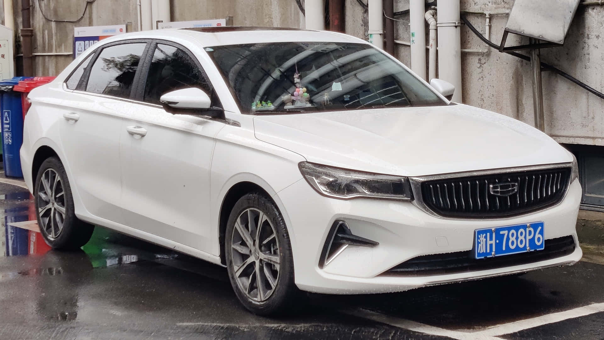 壁紙 — 一架時尚白色轎車停泊在濕漉漉的市區街道上，光澤表面映出倒影，並帶有藍色車牌。