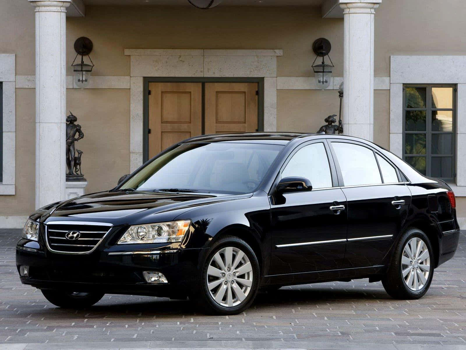 Hyundai Sonata 桌布 壁紙 — 一架時尚的黑色現代房車在日光下閃閃發光，停在一座擁有雲石柱和雕像的宏偉大宅前。