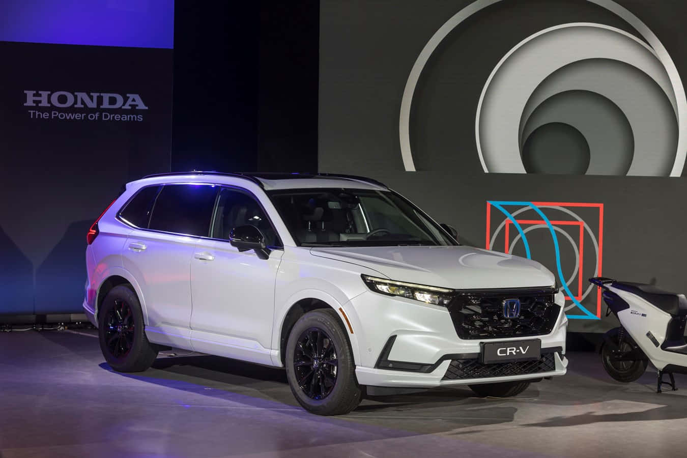Honda Cr-v 桌布 壁紙 — 一架時尚的白色本田CR-V SUV在戲劇性的藍色燈光下，以幾何背景在舞台上展示。