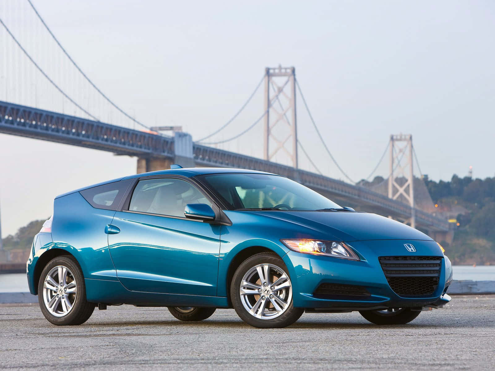 Honda Cr-z 桌布 壁紙 — 一架時尚的青綠色本田CR-Z跑車停泊在大型吊橋附近，背景有水域。
