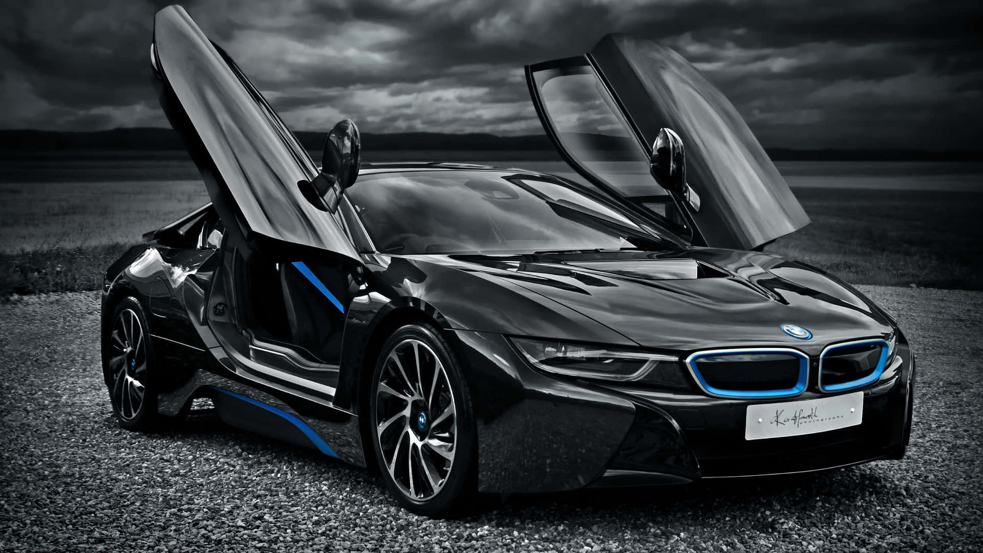 黑色BMW i8跑車，鷗翼門打開，停在碎石場上，天空風暴來臨。