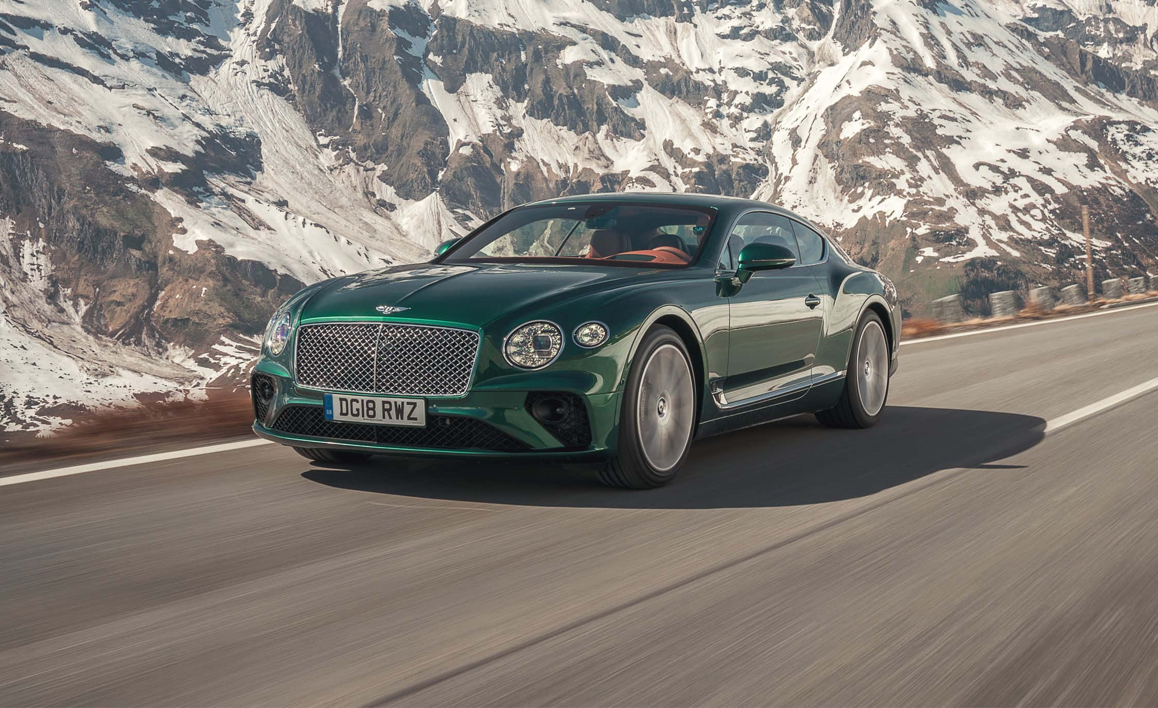 Bentley Continental Supersports 桌布 壁紙 — 一架時尚的綠色 Bentley Continental GT 沿著蜿蜒的山路行駛，背景是白雪覆蓋的山峰。