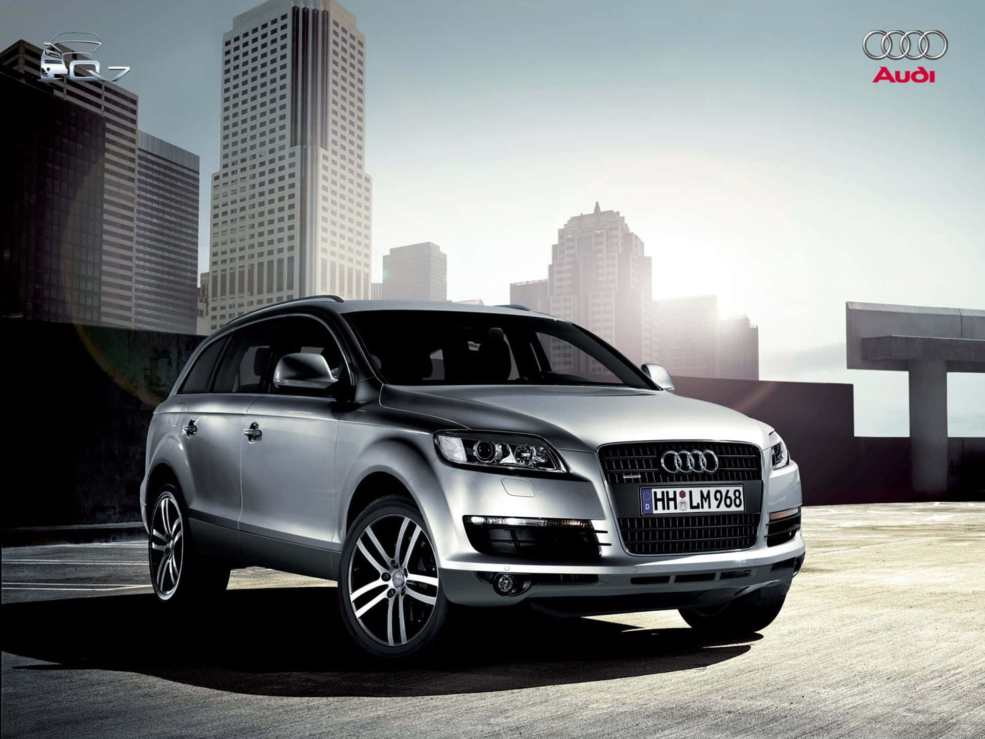 Audi Q7 桌布 壁紙 — 一架時尚的銀色 Audi Q7 SUV 停泊在天台上，現代城市天際線在柔和的晨光中閃耀。