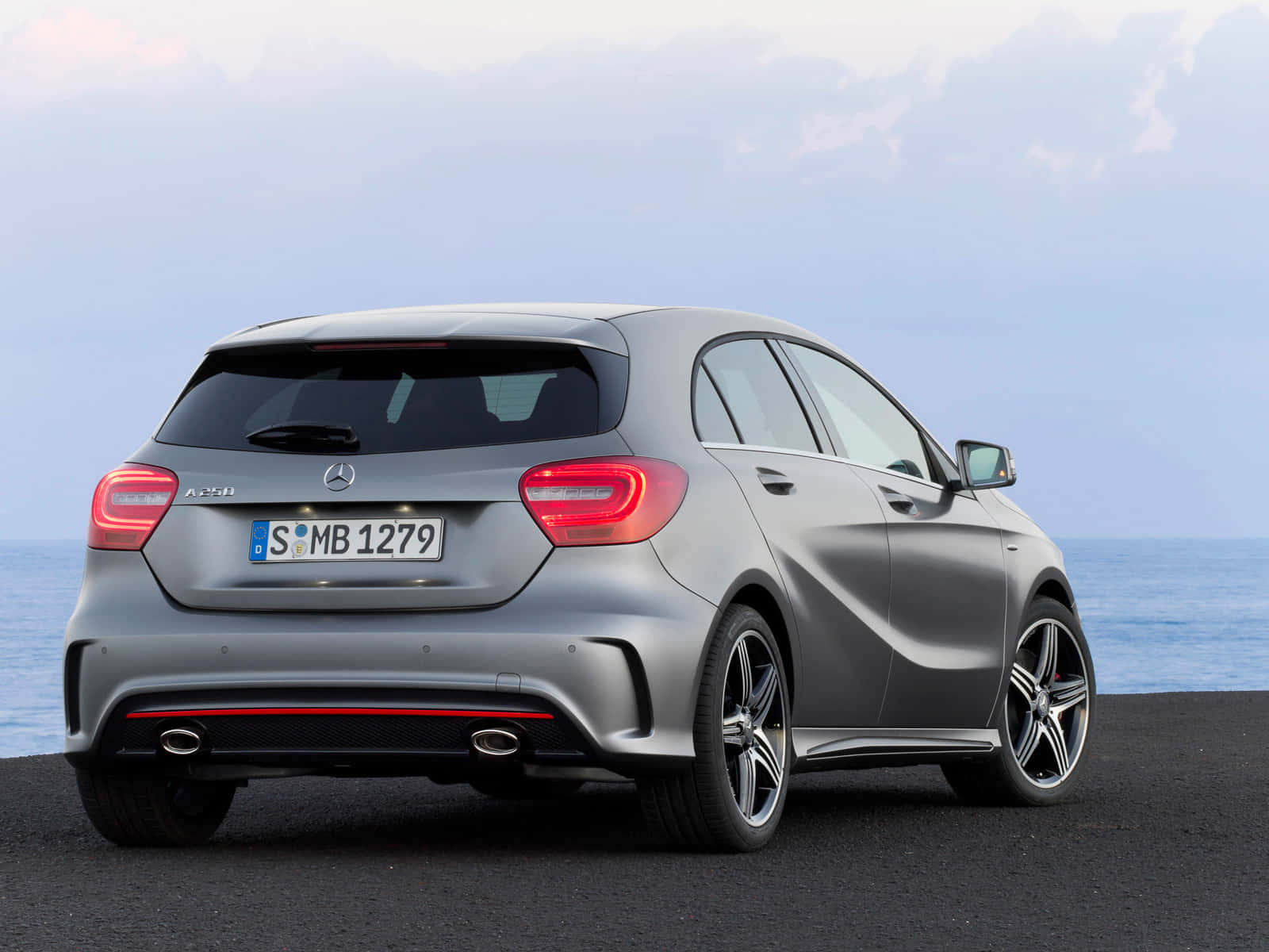 Mercedes Benz A-class 桌布 壁紙 — 一架時尚的銀色 Mercedes A45 AMG 停在黑暗的路面上，背景是海洋和陰天。