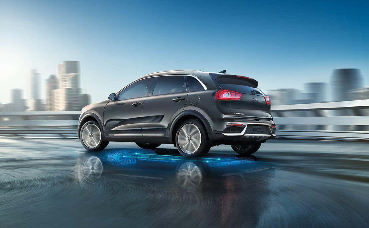 Kia Niro 桌布 壁紙 — 一架時尚灰色SUV在濕潤的城市橋上高速行駛，模糊的摩天大樓在晴朗藍天下。