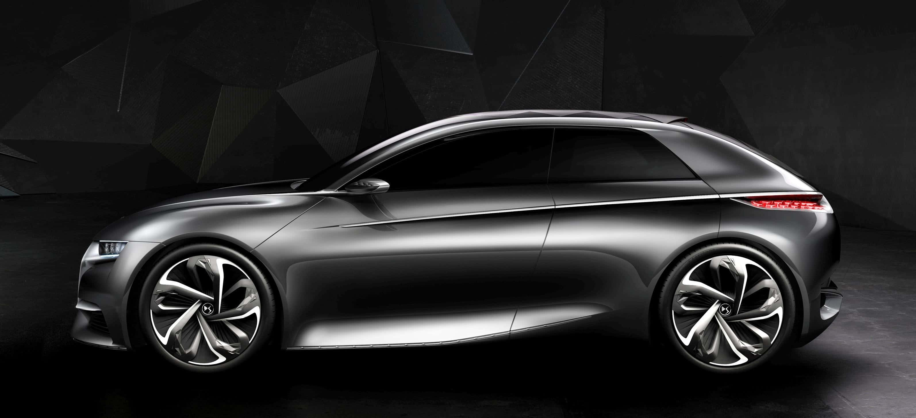 Citroen Divine Ds Concept 桌布 壁紙 — 一架時尚的銀色未來感旅行車，帶有發光的紅色尾燈，停在深色幾何牆前。