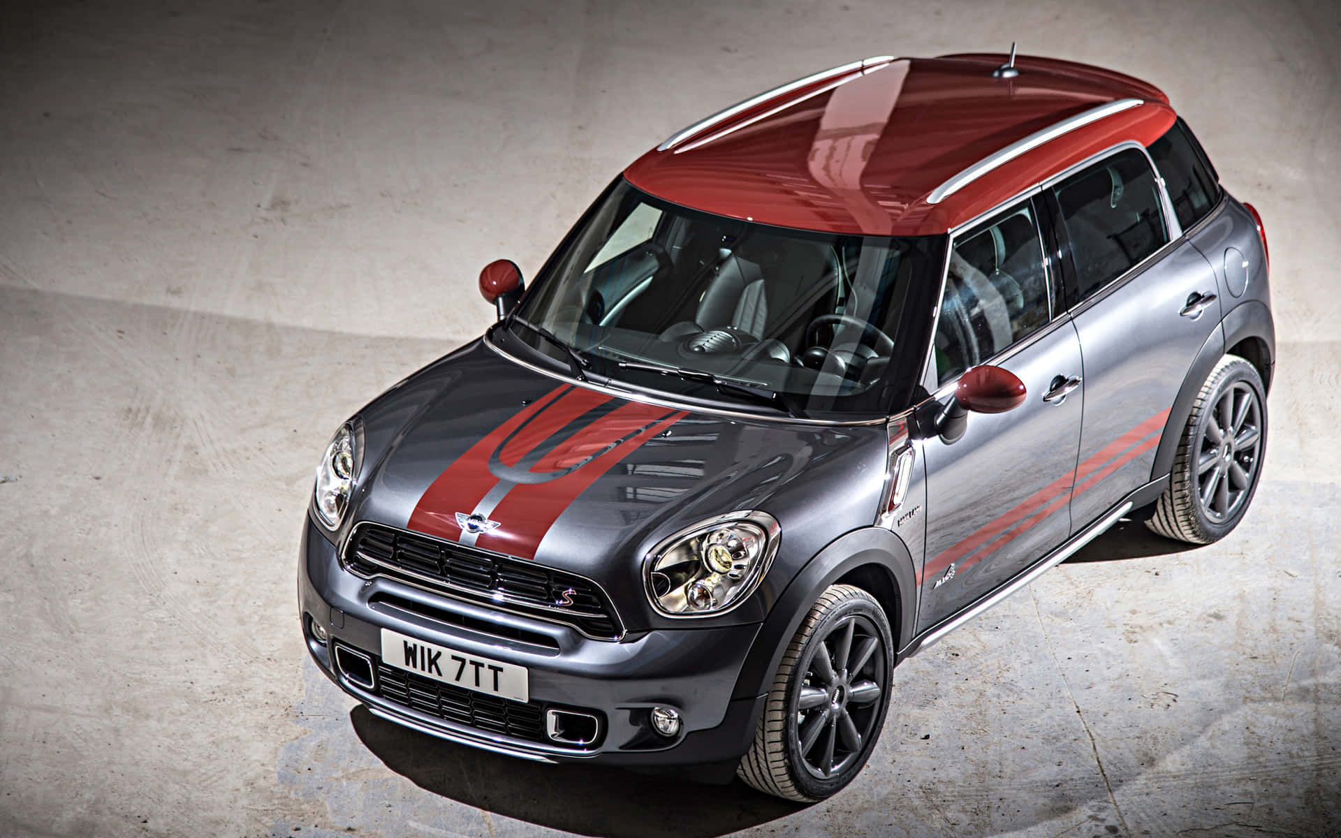  壁紙 — 一架時尚的銀色MINI Countryman，紅色車頂和賽車條紋，停在混凝土車道上。