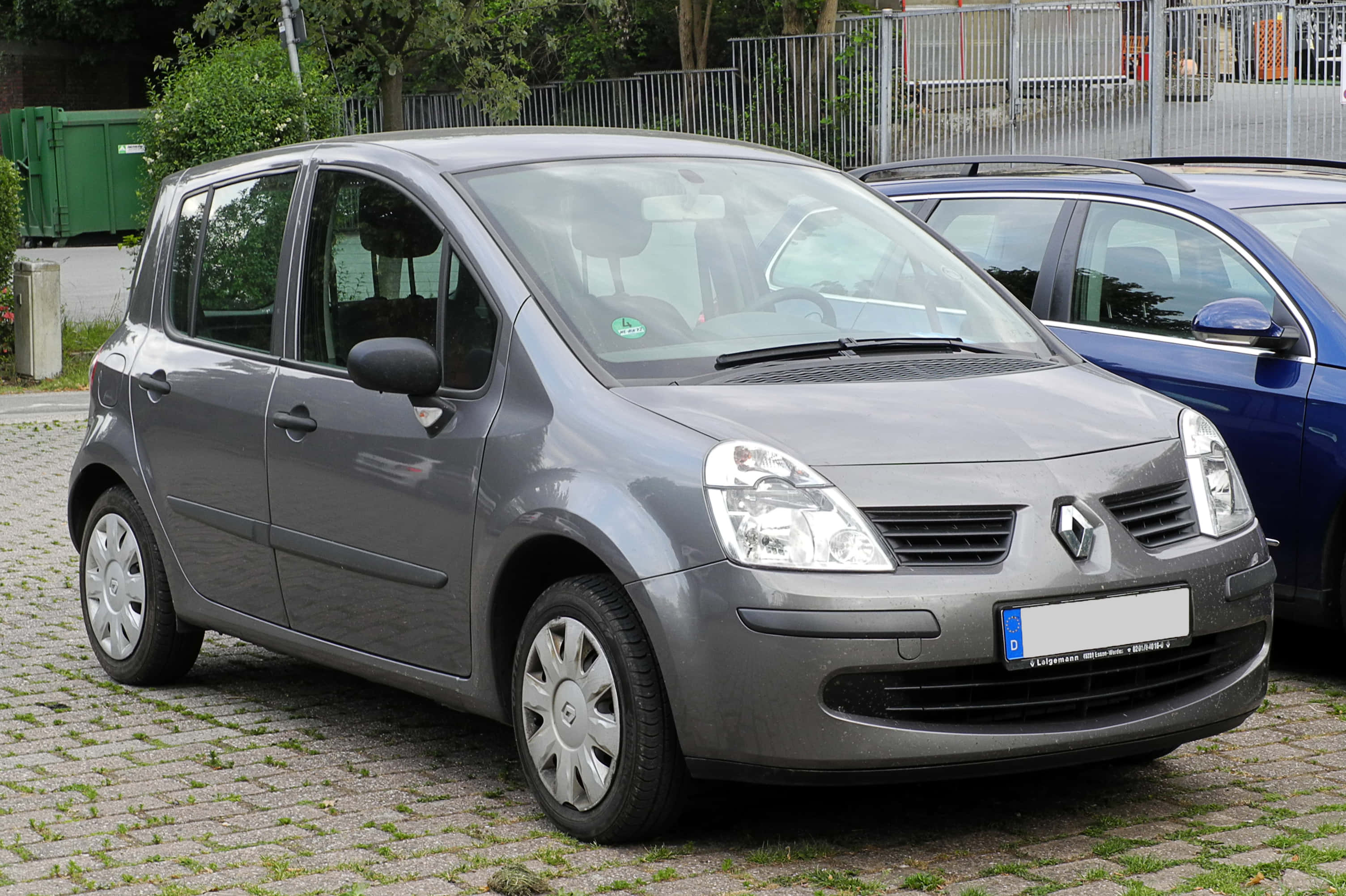 Renault Modus 桌布 壁紙 — 一架時尚的灰色雷諾Scenic停泊在鵝卵石地上，背景有綠化和圍欄。