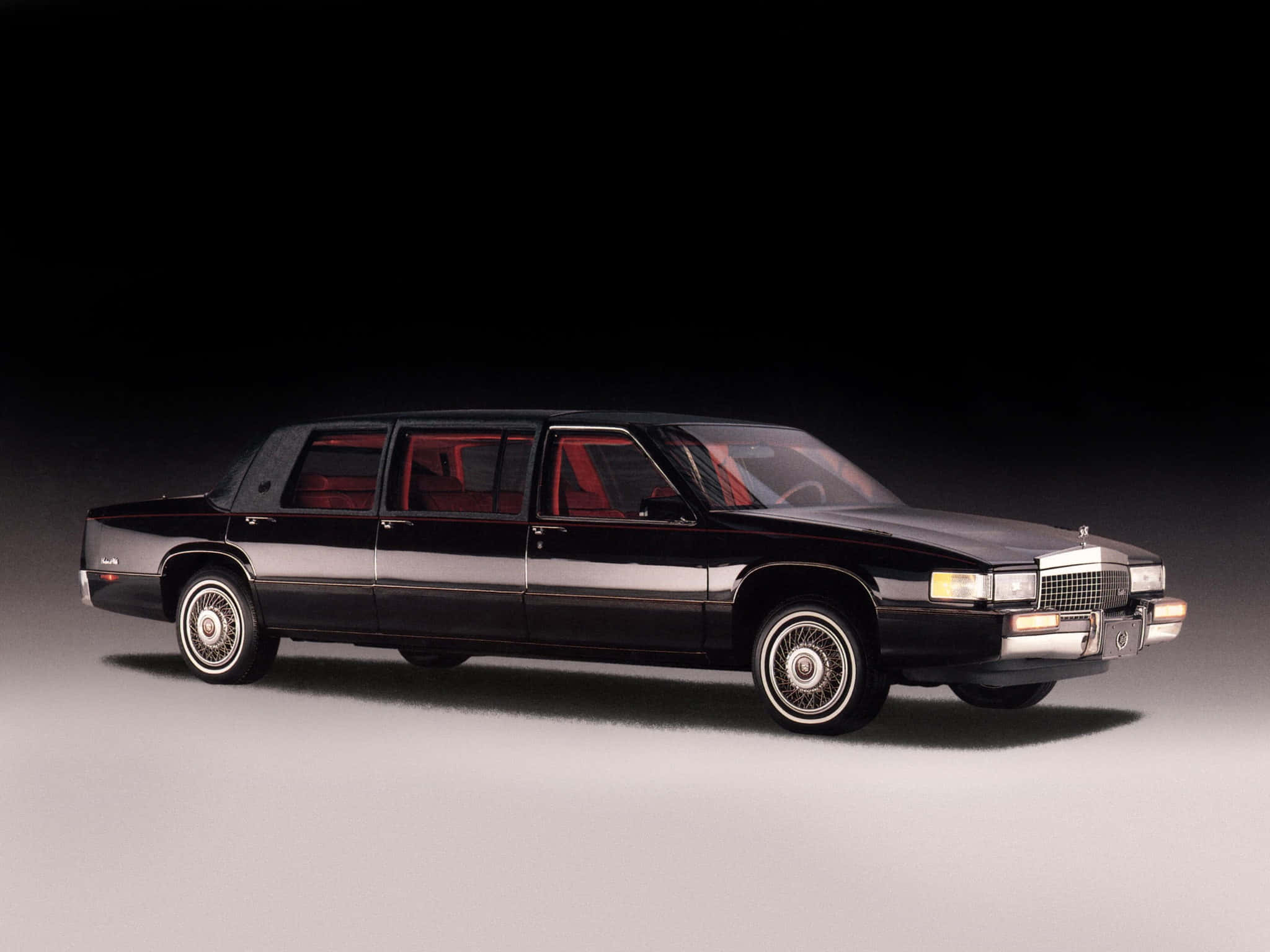 Cadillac Deville 桌布 壁紙 — 一架時尚黑色豪華轎車配紅色內飾，在深色漸變背景前展現奢華與力量。