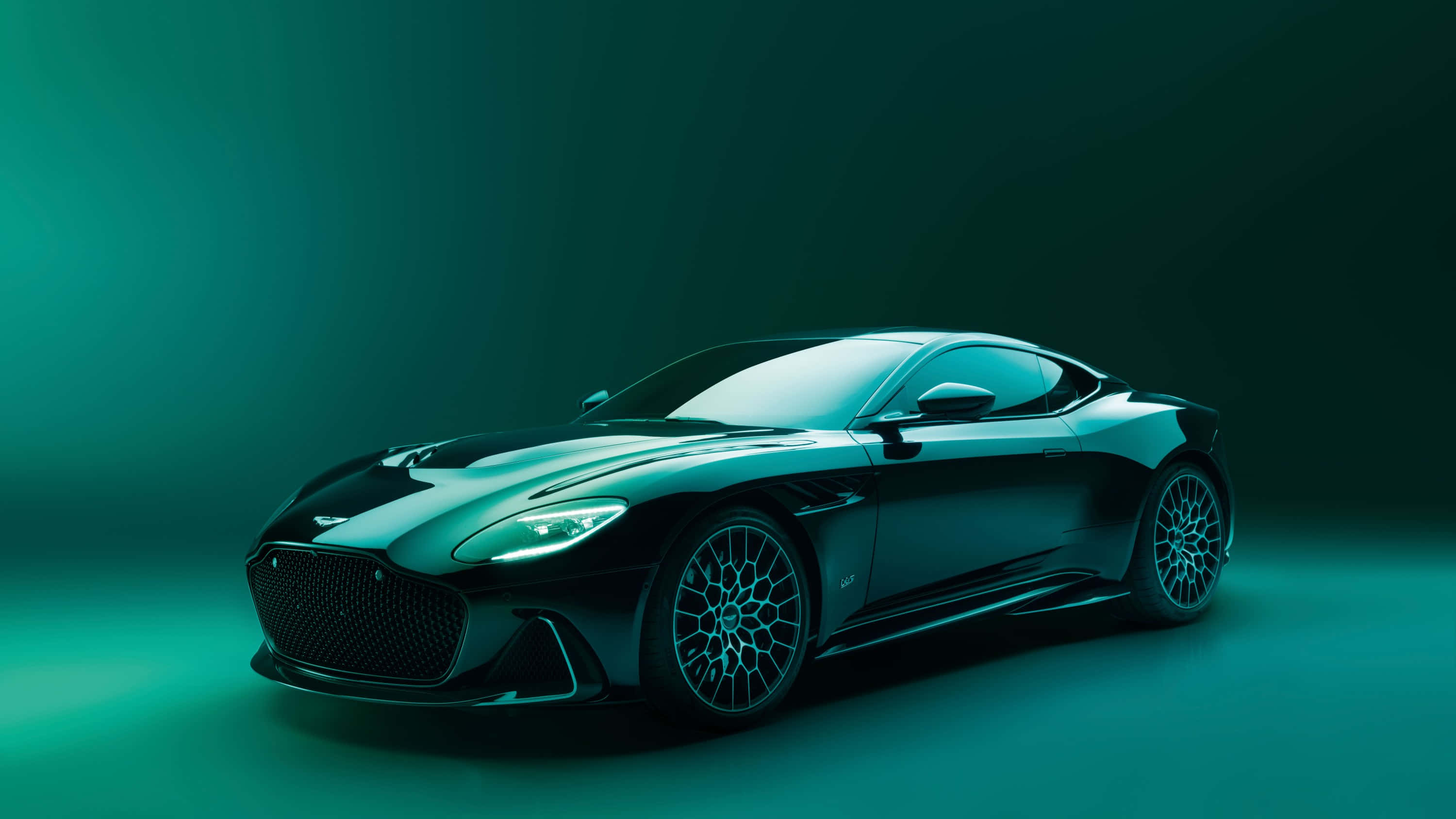 Aston Martin Dbs Superleggera 桌布 壁紙 — 一架時尚的黑色Aston Martin跑車在戲劇性的青綠色工作室燈光下發光，背景為漸變色。