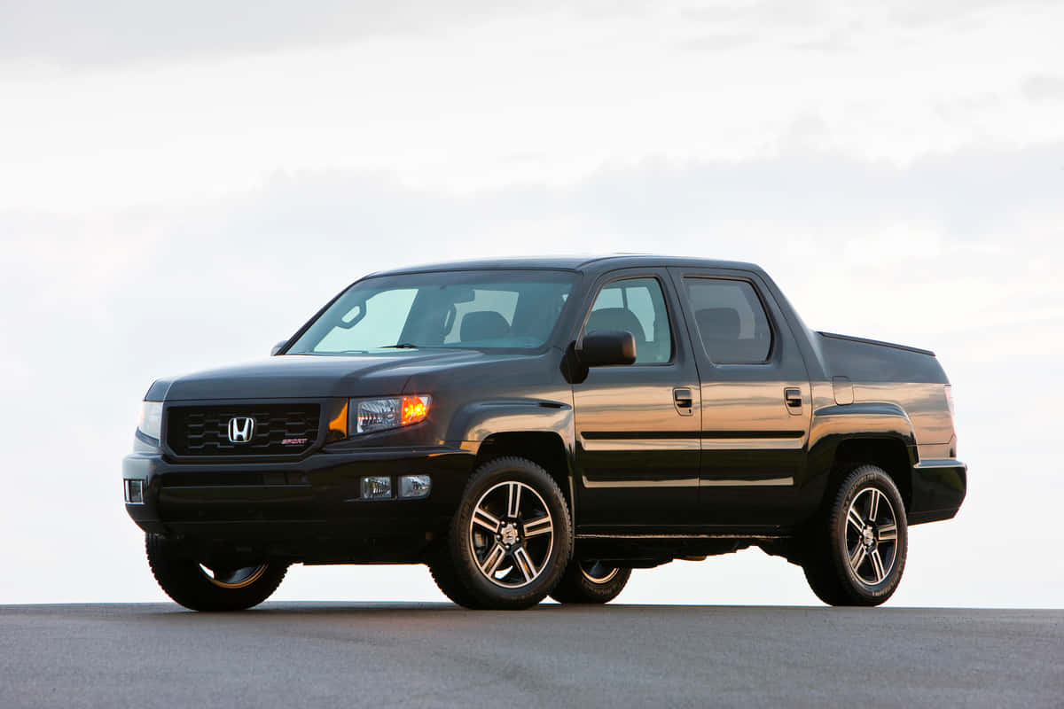 Honda Ridgeline 桌布 壁紙 — 一架時尚的黑色本田Ridgeline皮卡車停在鋪砌的路面上，柔和的多雲天空下，黃金時段的光線突顯其輪廓。