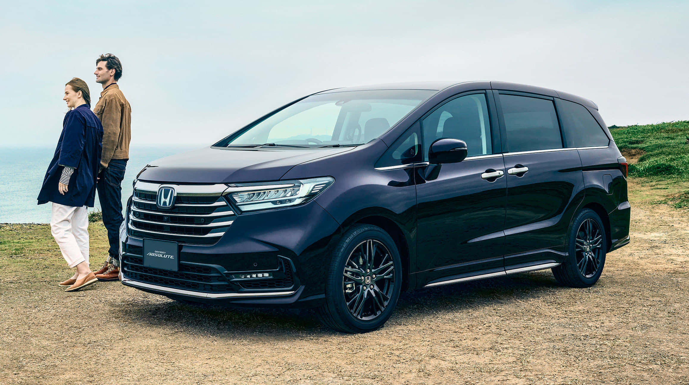 Honda Odyssey 桌布 壁紙 — 一架時尚深藍色本田Odyssey小型貨車停泊在海岸懸崖上，一對情侶站在旁邊俯瞰海洋。