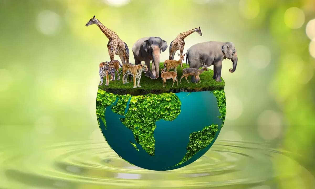  壁紙 — 一個被茂密綠色植物覆蓋的地球儀，表面上有各種動物，如長頸鹿、大象和老虎，站在柔和的綠色散景背景前。