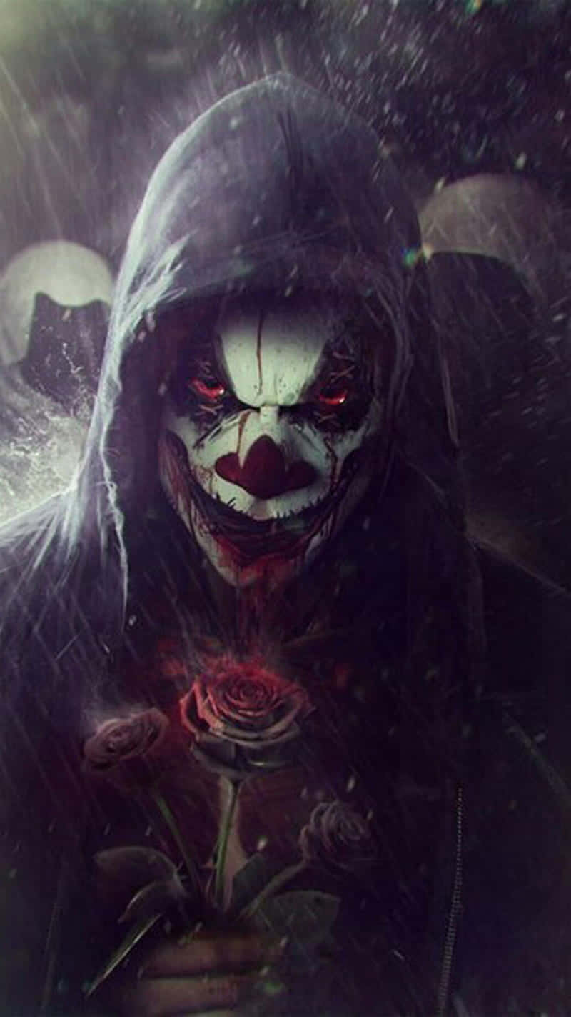  壁紙 — 一個戴著兜帽的小丑，眼睛發出紅光，化妝帶血，在黑暗的雨中手持一朵紅玫瑰。