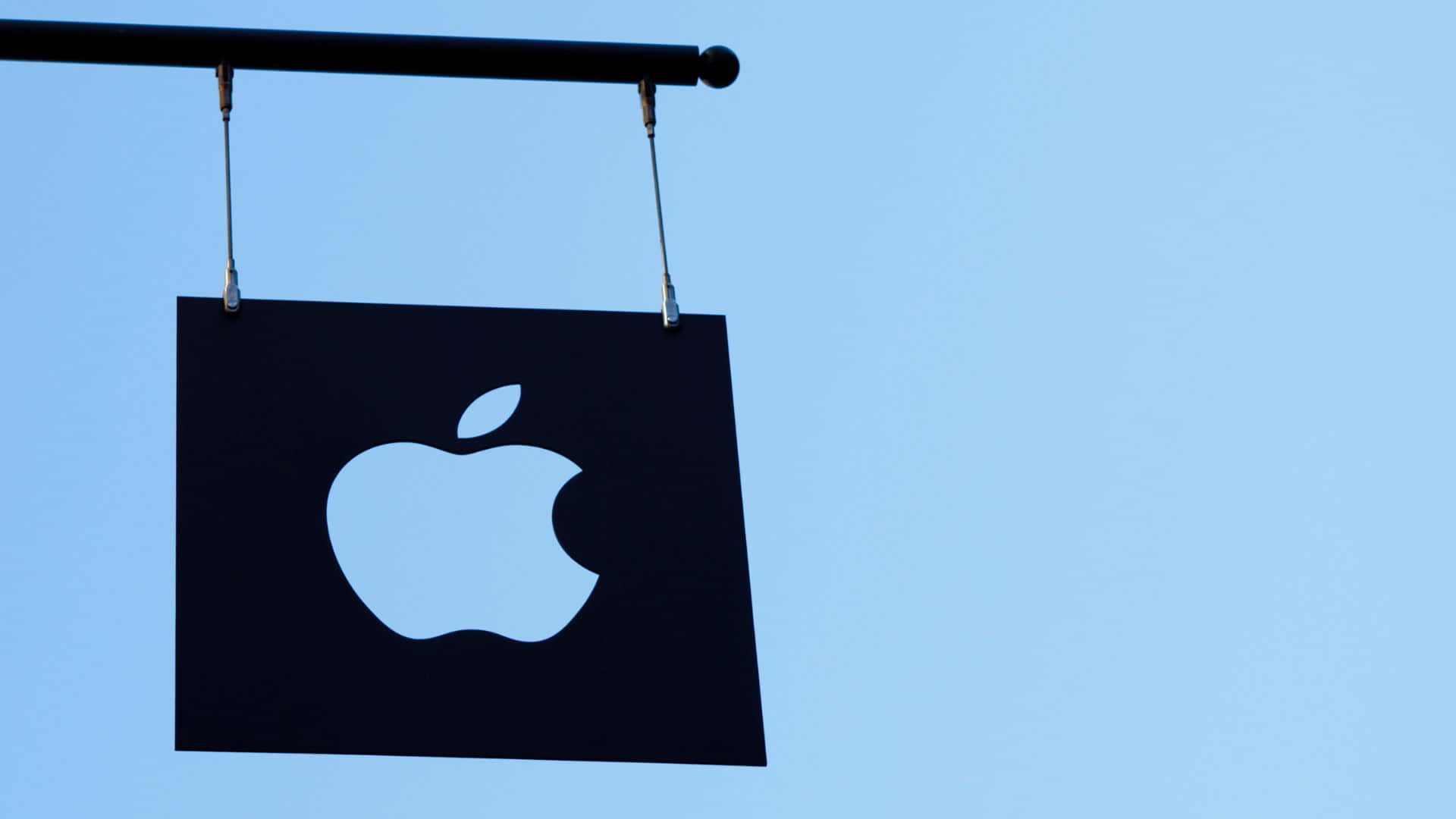 黑色Apple標誌牌懸掛在清澈的藍天下。
