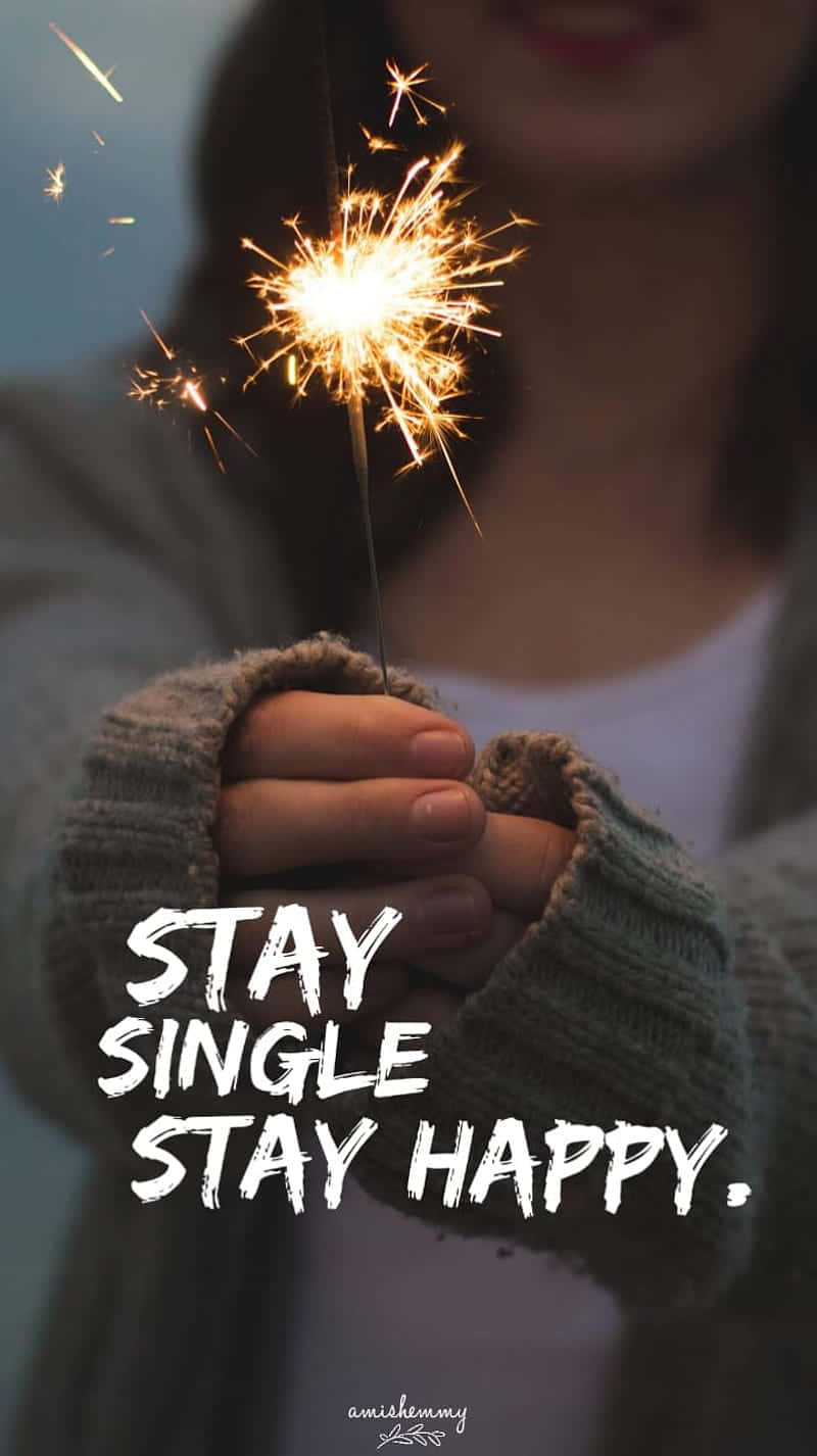  壁紙 — 一個人手持明亮閃爍的煙花，背景柔和模糊，並有粗體文字 stay single stay happy。