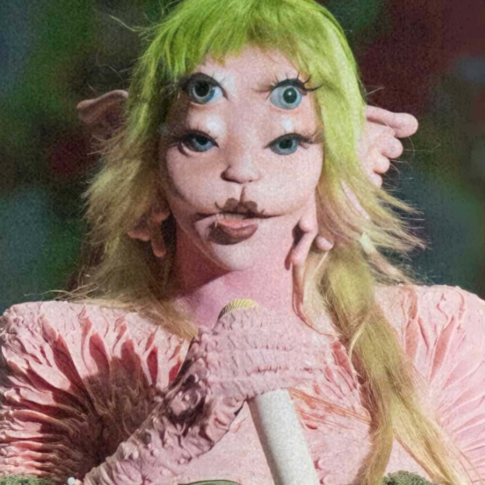  壁紙 — 一個有四隻眼睛、綠色頭髮和紋理粉紅色衣服的人拿著咪高峰的超現實肖像。