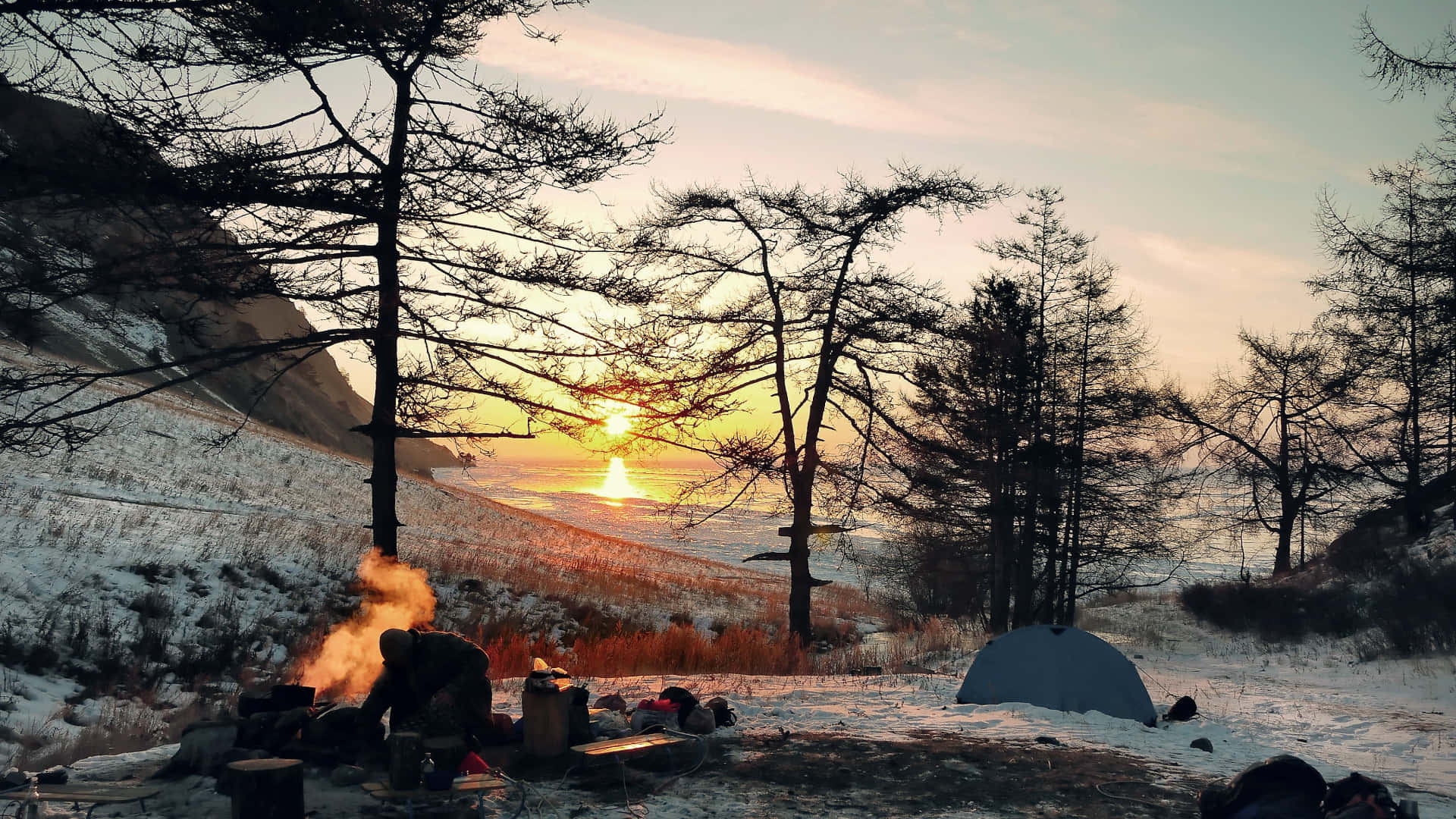 在雪山露營，夕陽，營火和帳篷。