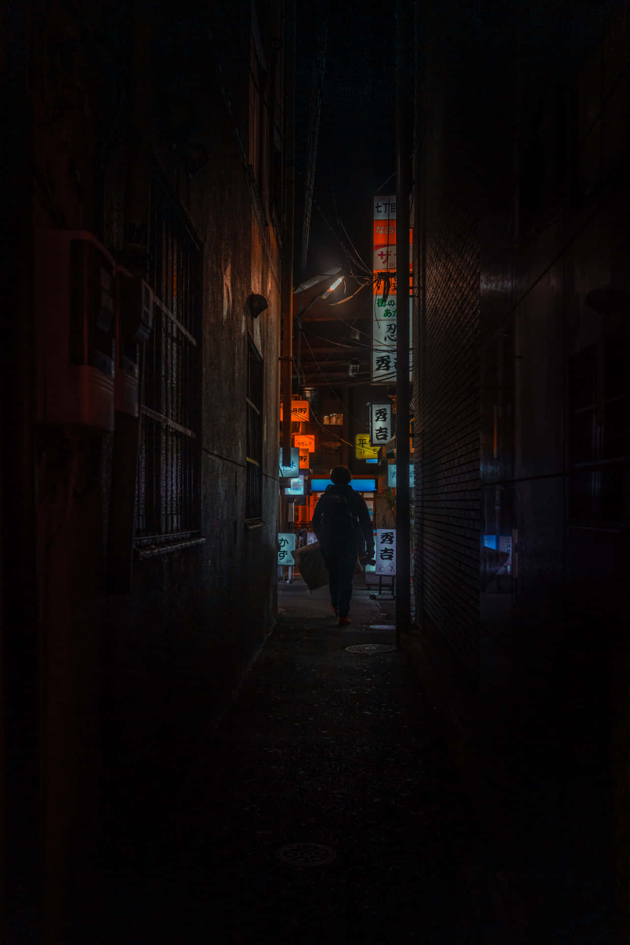  壁紙 — 一個孤獨的身影在夜晚沿著東京一條狹窄的小巷行走，被發光的霓虹燈招牌和路燈照亮。