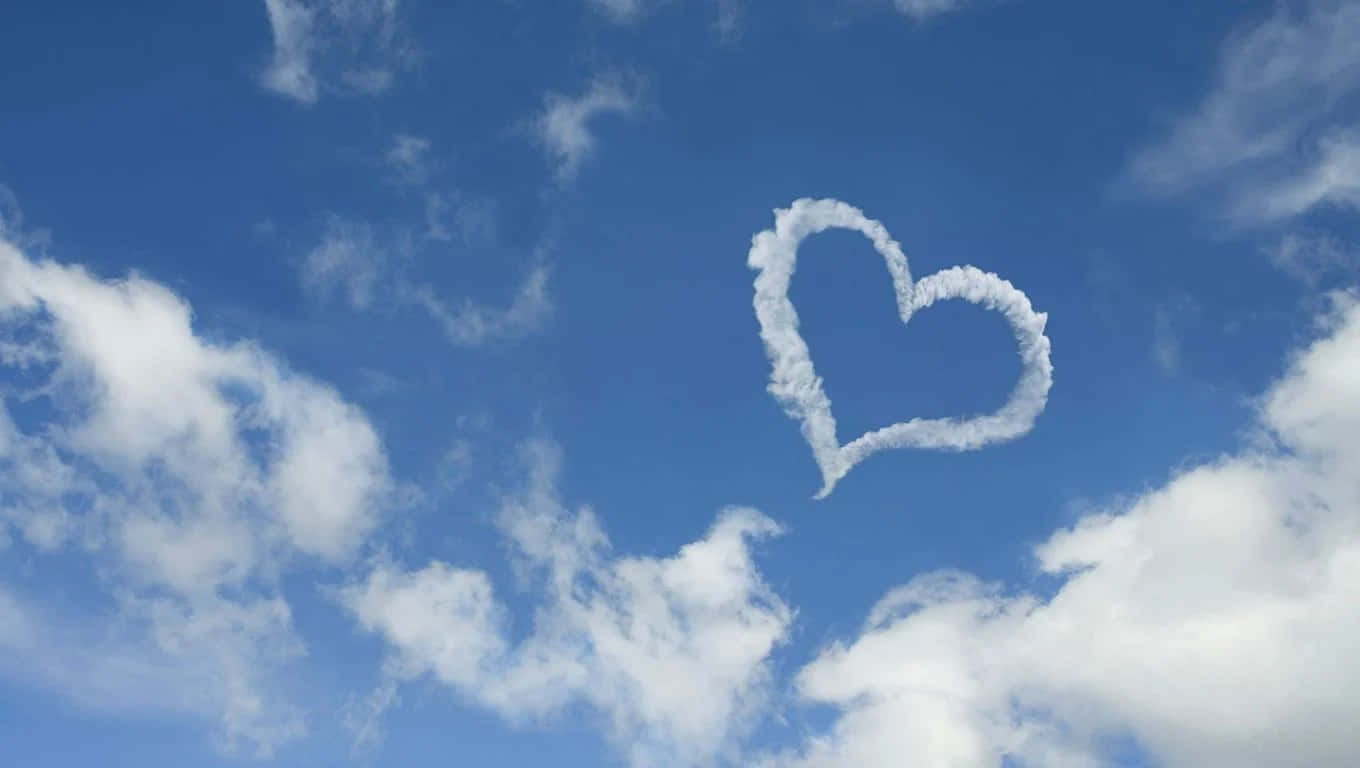 I Love God 桌布 壁紙 — 一個心形雲朵在點綴著蓬鬆白雲的鮮豔藍天中優雅飄浮。