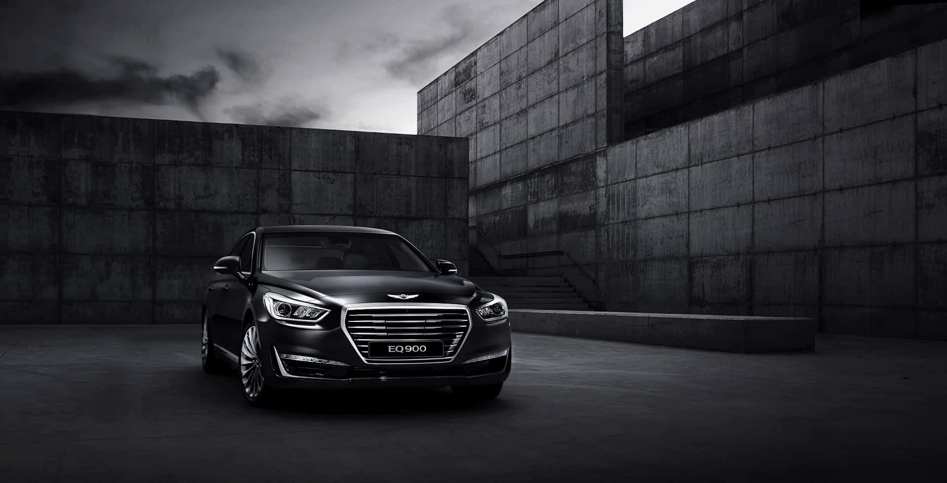 Genesis G80 桌布 壁紙 — 一架時尚的黑色豪華轎車停泊在簡樸的混凝土庭院中，天空陰沉多雲。