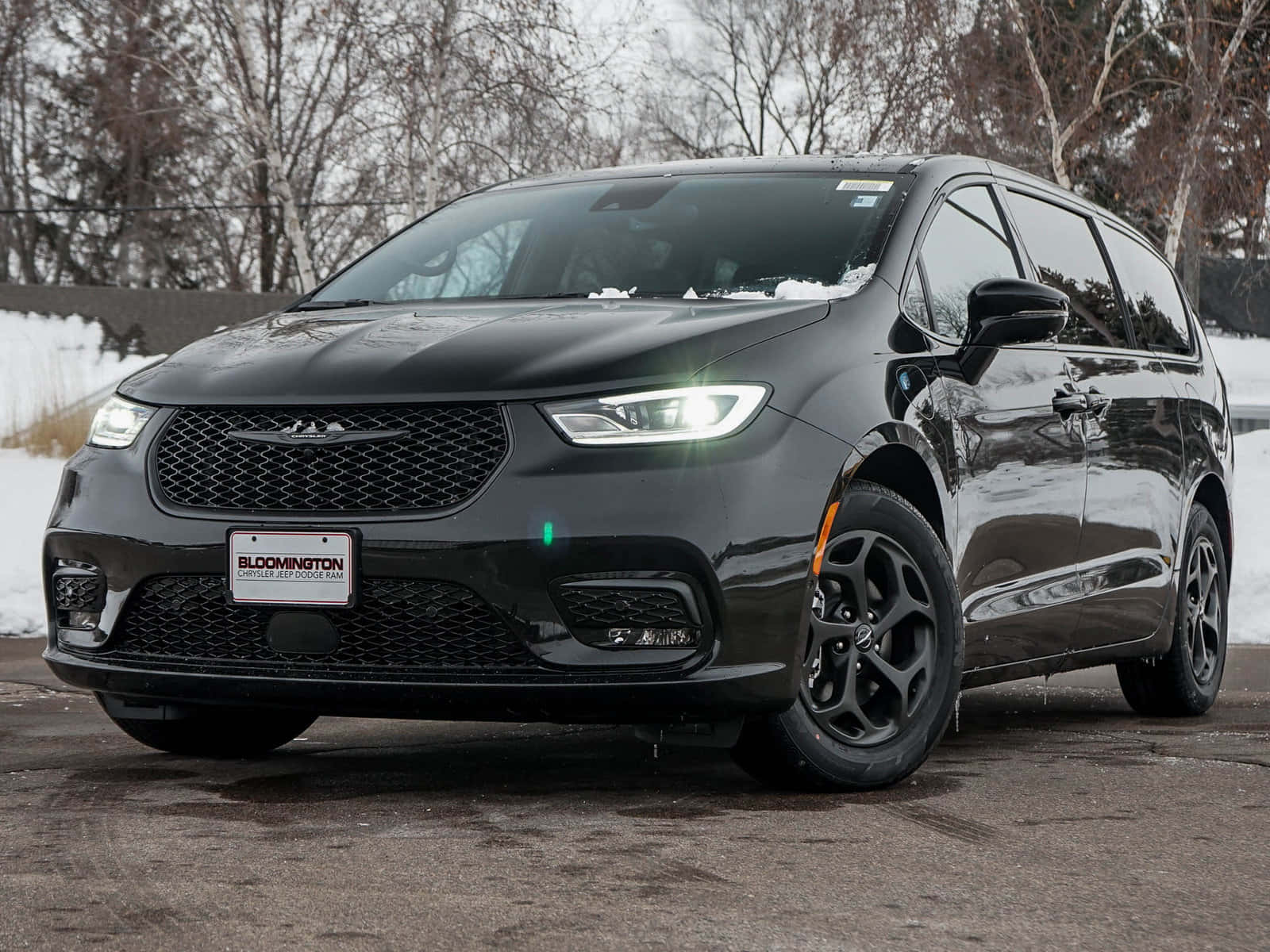 Chrysler Pacifica 桌布 壁紙 — 一架時尚的黑色克萊斯勒小型貨車在冬日陽光下閃閃發光，車頂上積雪，後面是光禿禿的樹木。