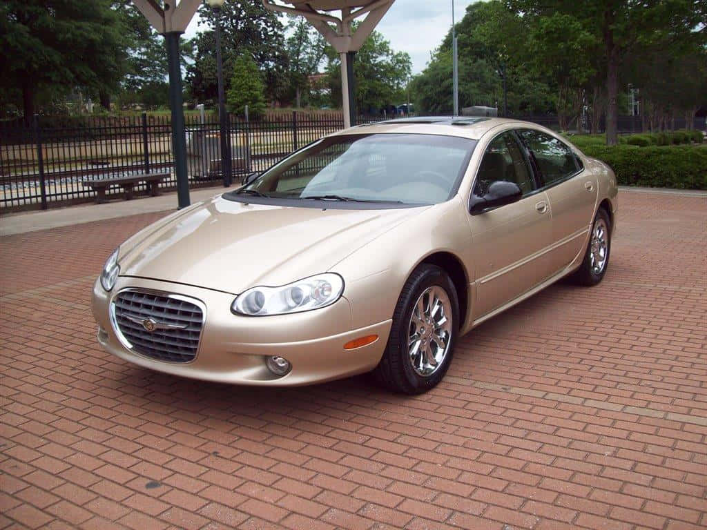 Chrysler Lhs 桌布 壁紙 — 一輛金色克萊斯勒轎車停泊在紅磚庭院上，上方有蓋涼亭，背景有綠樹。
